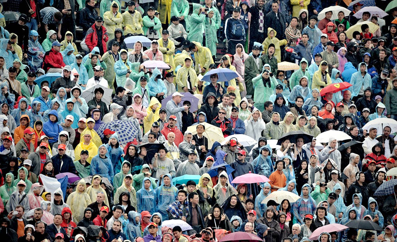 Spectators watch Formula One's Chinese Grand Prix in Shanghai on April 18, 2010.  Defending champion Jenson Button delivered a perfectly judged drive in treacherous wet conditions to win the dramatic Chinese Grand Prix ahead of his McLaren teammate Lewis Hamilton while Mercedes driver Nico Rosberg of Germany finished in 3rd position.   AFP PHOTO / PHILIPPE LOPEZ (Photo credit should read PHILIPPE LOPEZ/AFP/Getty Images)