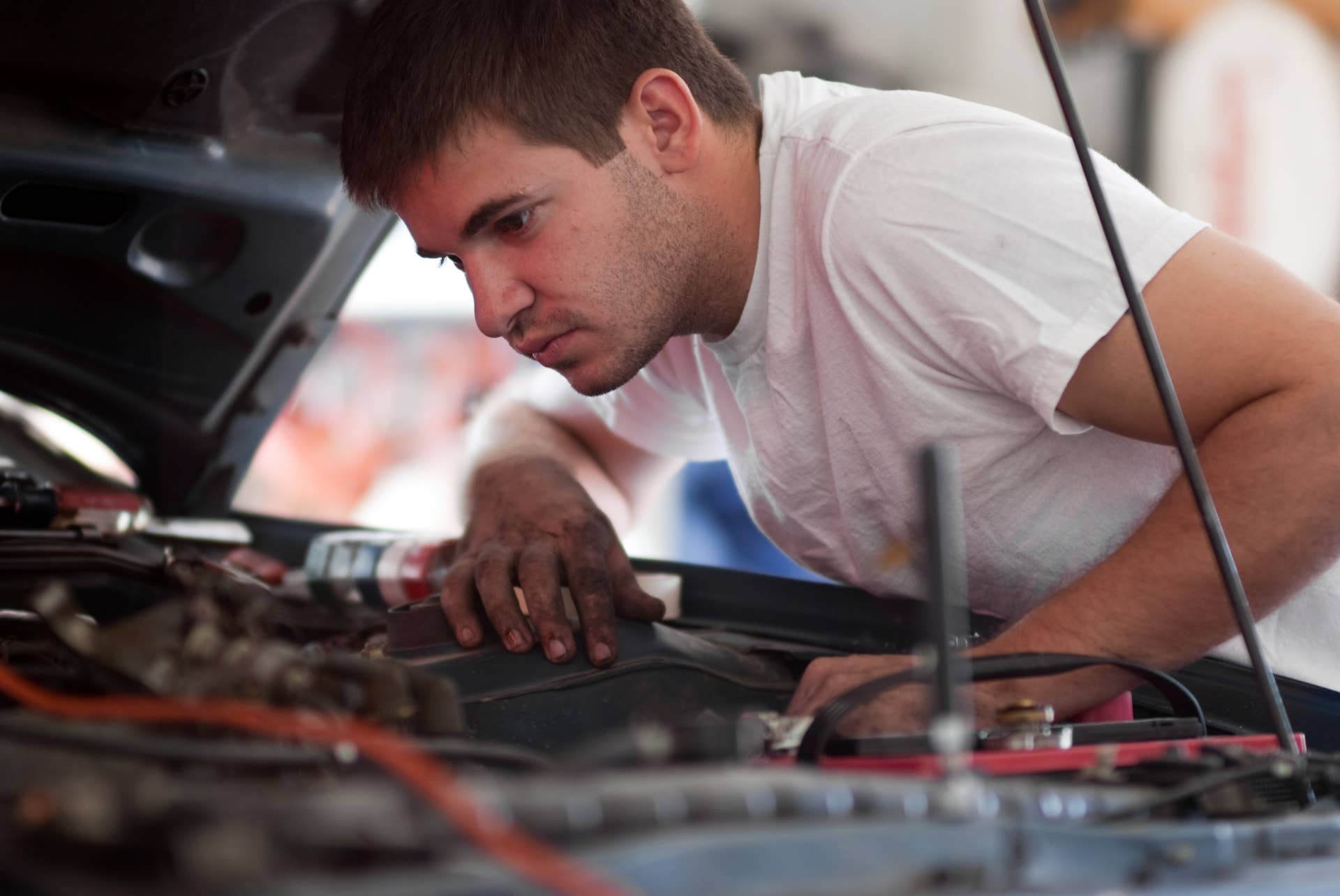 Car repair mechanic fixing auto. Man working on car in garage. At home do it yourself. Examine / inspect engine compartment for trouble; diagnose and fix / correct problem; preventative maintenance.