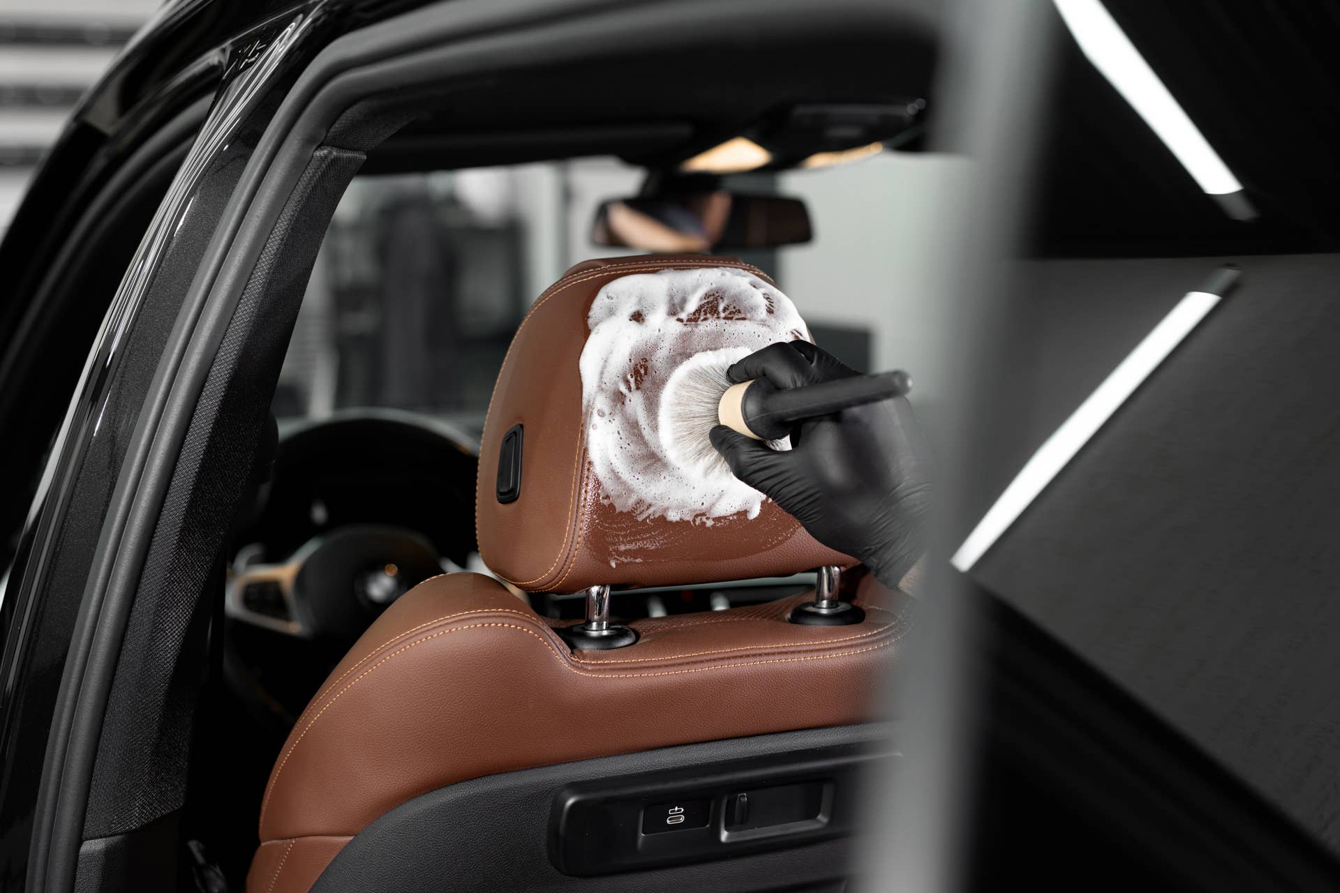 Washing with foam with a brush of the interior, leather car seats. Car detailing service