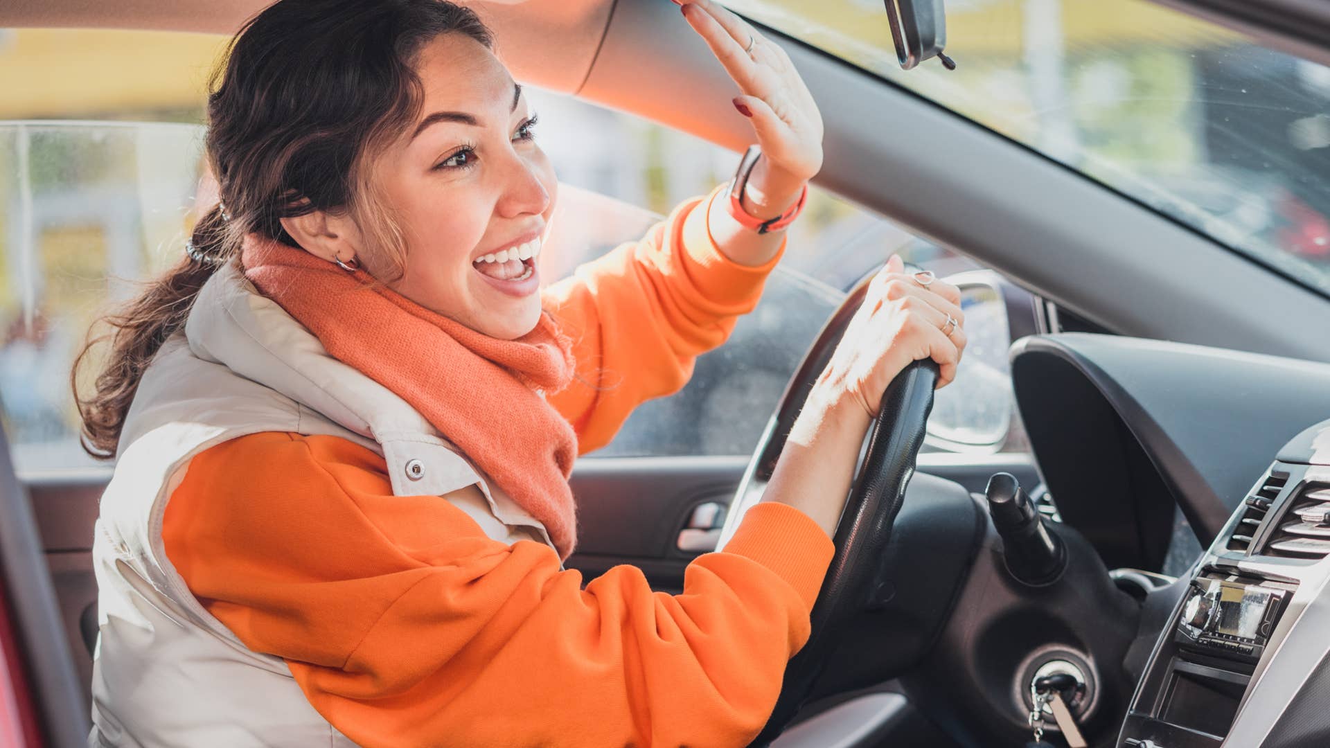 Polite woman driver raised her hand as a sign of respect and says thank you for giving way. Relations between people in traffic regulations