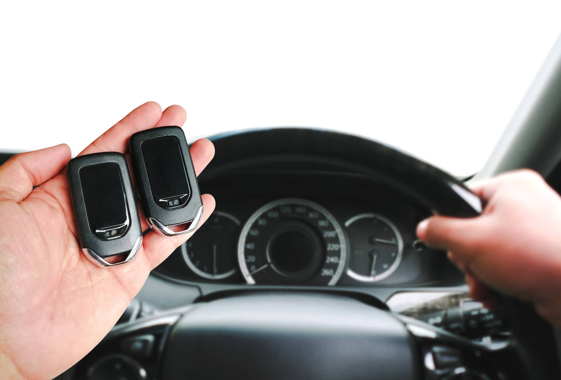 Driver hand holding a car keyless entry remote for engine start or stop. Two keyless car remotes in the driver hand for comparison. copy space, Concept of keyless car remote technology.
