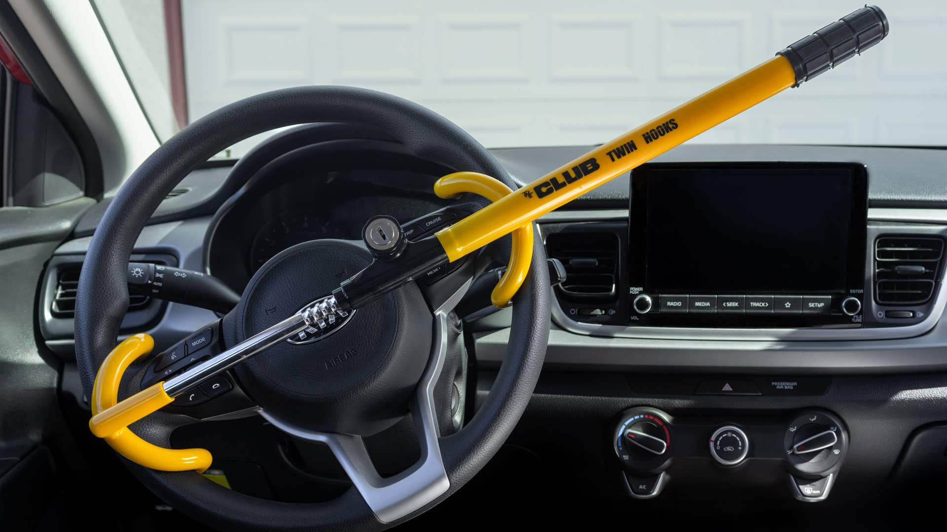 Victorville, CA, USA – August 11, 2022: The Club Twin Hook steering wheel security lock in yellow attached to a Kia Rio car.