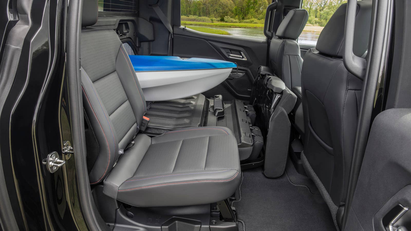 A view showing the 2024 Silverado EV RST’s Multi-Flex Midgate from the second row, holding a kayak.