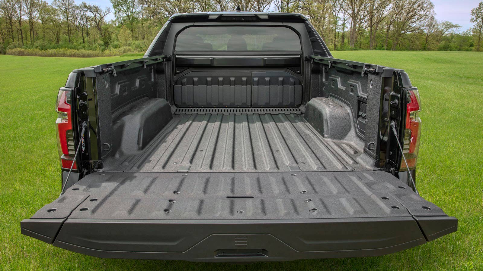 A rear shot of the 2024 Silverado EV RST with its tailgate down and Multi-Flex Midgate up.