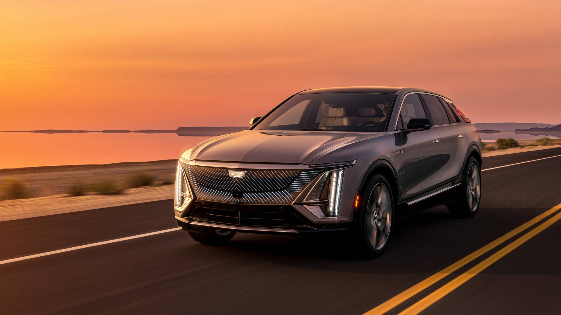 The Cadillac LYRIQ in Satin Steel Metallic driving at sunset. Image shown displays preproduction model. Actual production model will vary. 2023 Cadillac LYRIQ Debut Edition available summer 2022, by reservation only. Additional LYRIQ models available starting fall 2022, see dealer for details.