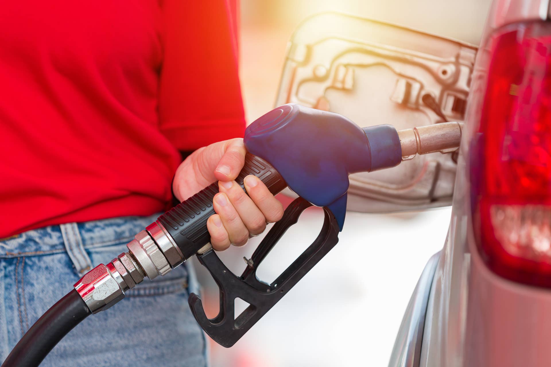 Hands of attendant service female worker refuelling car at gas station. Assistant worker refuelling car at petrol station