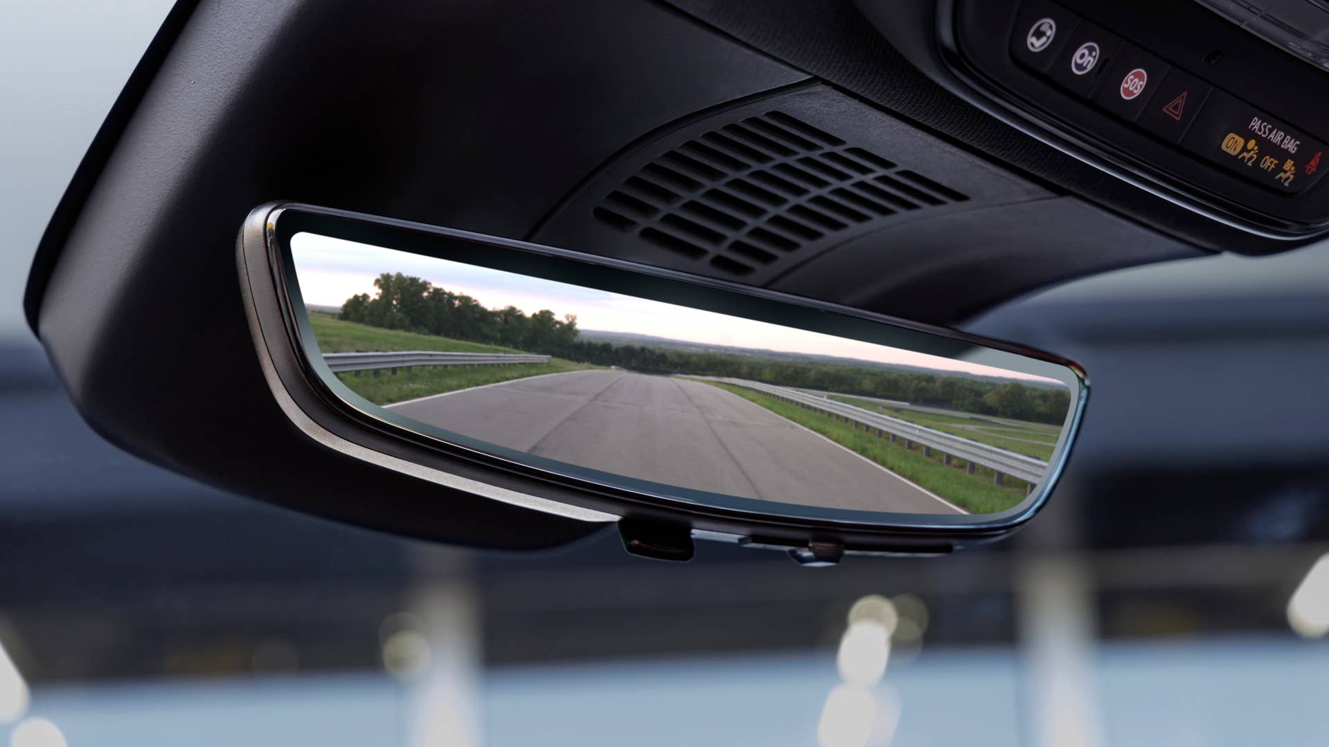 View of a road and trees in rearview mirror on 2024 Chevrolet Blazer EV SS in Radiant Red Tintcoat. Preproduction model shown. Actual production model may vary. 2024 Chevrolet Blazer EV available Spring 2023.