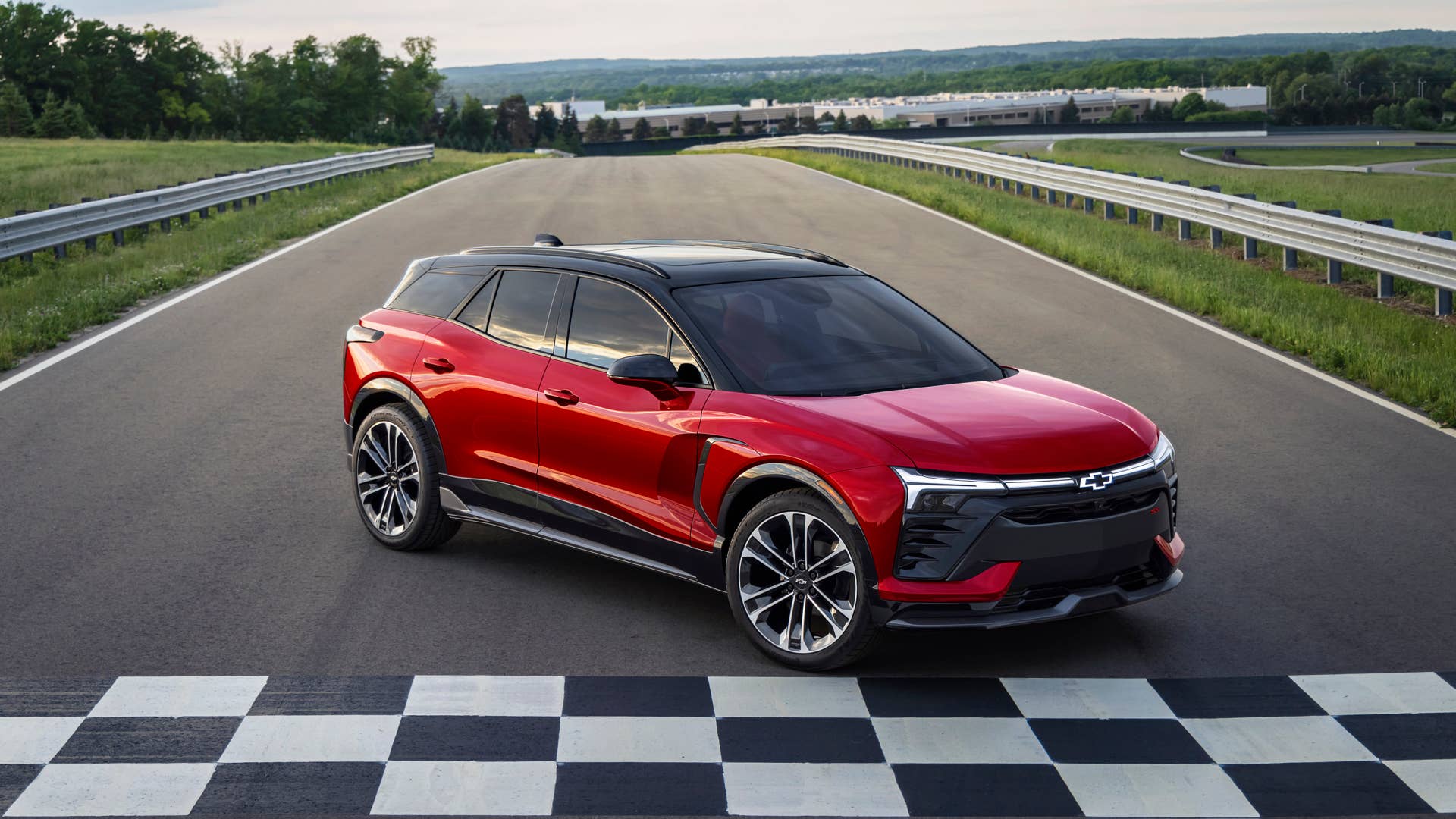 Seven-eighths view of 2024 Chevrolet Blazer EV SS in Radiant Red Tintcoat parked in front of a checkered finish line. Preproduction model shown. Actual production model may vary. 2024 Chevrolet Blazer EV available Spring 2023.