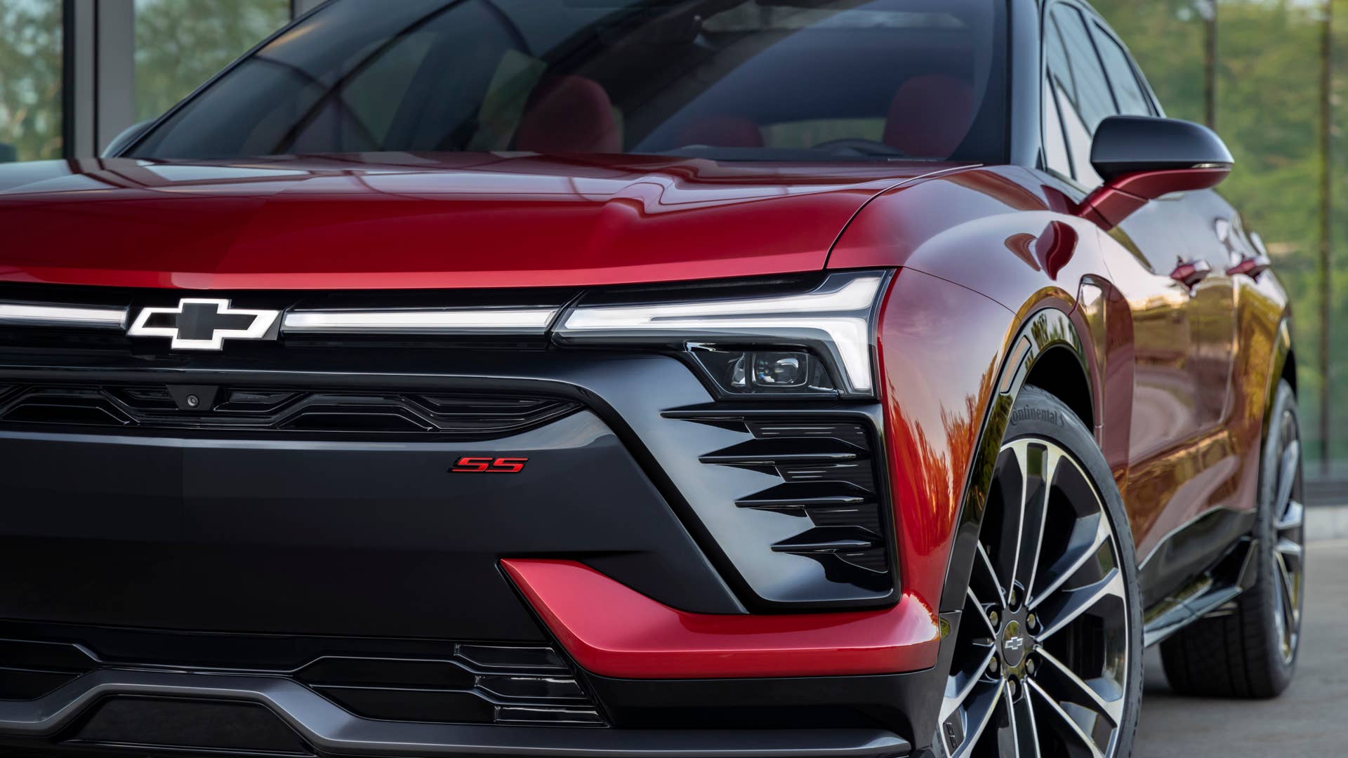 Close up of front grille, illuminated headlights and wheel on 2024 Chevrolet Blazer EV SS in Radiant Red Tintcoat. Preproduction model shown. Actual production model may vary. 2024 Chevrolet Blazer EV available Spring 2023.