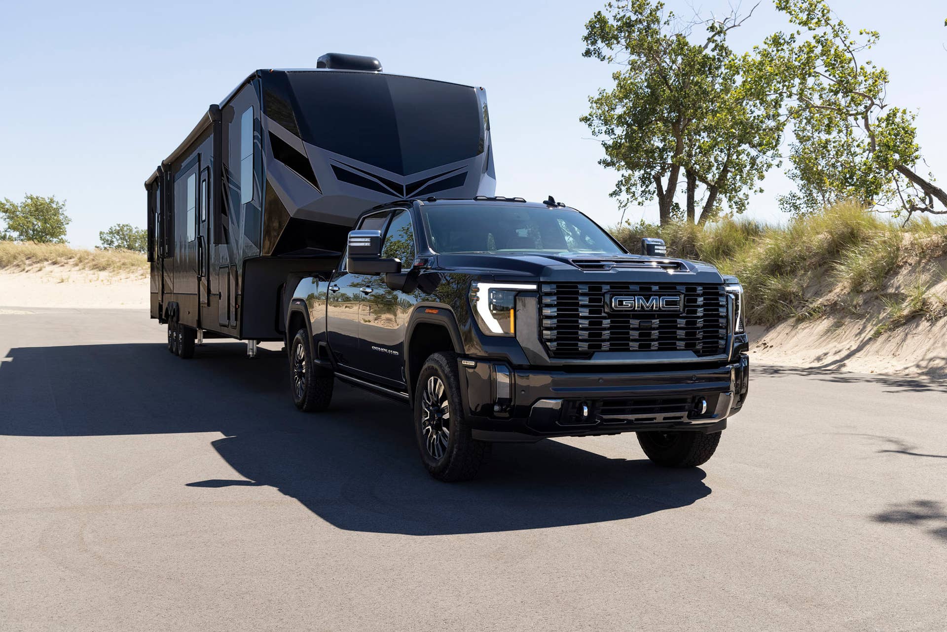 Front 3/4 view of the 2024 GMC Sierra 2500 HD Denali Ultimate towing a trailer