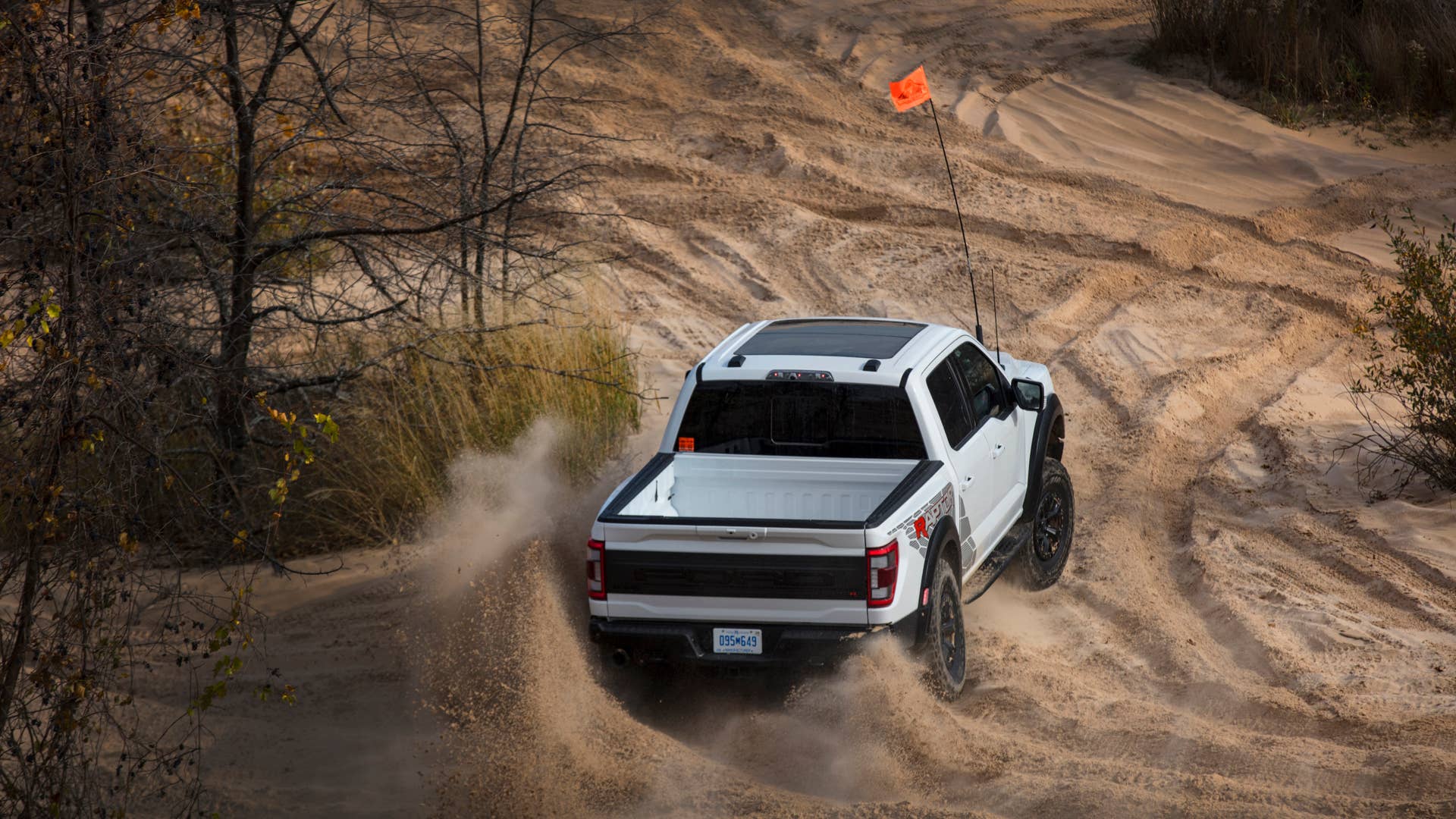 Preproduction 2023 F-150 Raptor R with aftermarket flag and optional equipment. Available late 2022. Professional driver on a closed course. Always consult the Raptor supplement to the Owner’s Manual before off-road driving, know your terrain and trail difficulty, and use appropriate safety gear.