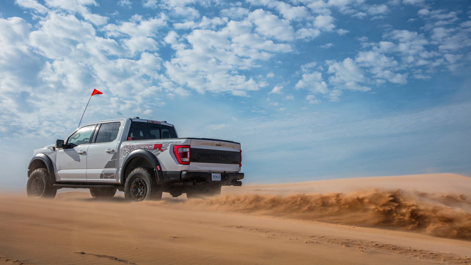 Preproduction 2023 F-150 Raptor R with aftermarket flag and optional equipment. Available late 2022. Professional driver on a closed course. Always consult the Raptor supplement to the Owner’s Manual before off-road driving, know your terrain and trail difficulty, and use appropriate safety gear.