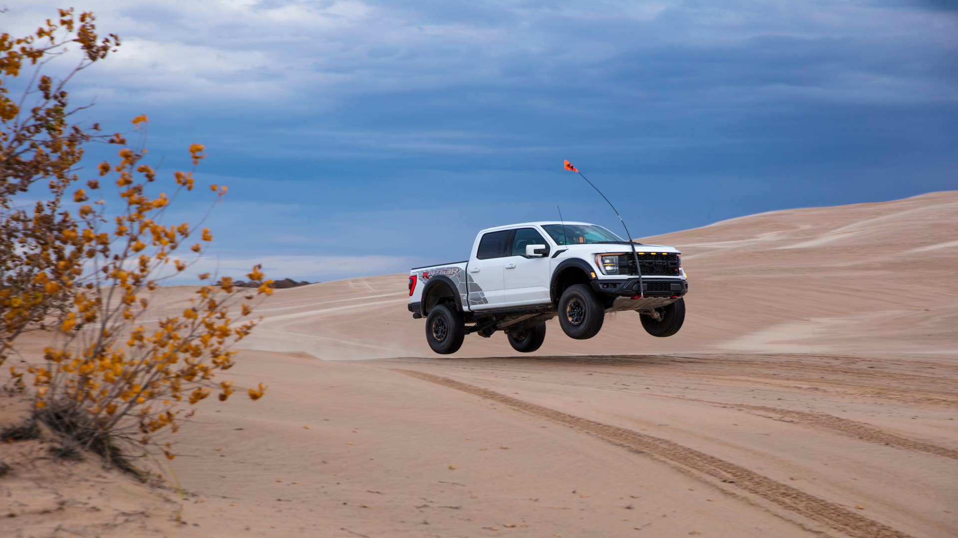 Preproduction 2023 F-150 Raptor R with aftermarket flag and optional equipment. Available late 2022. Professional driver on a closed course. Always consult the Raptor supplement to the Owner’s Manual before off-road driving, know your terrain and trail difficulty, and use appropriate safety gear.