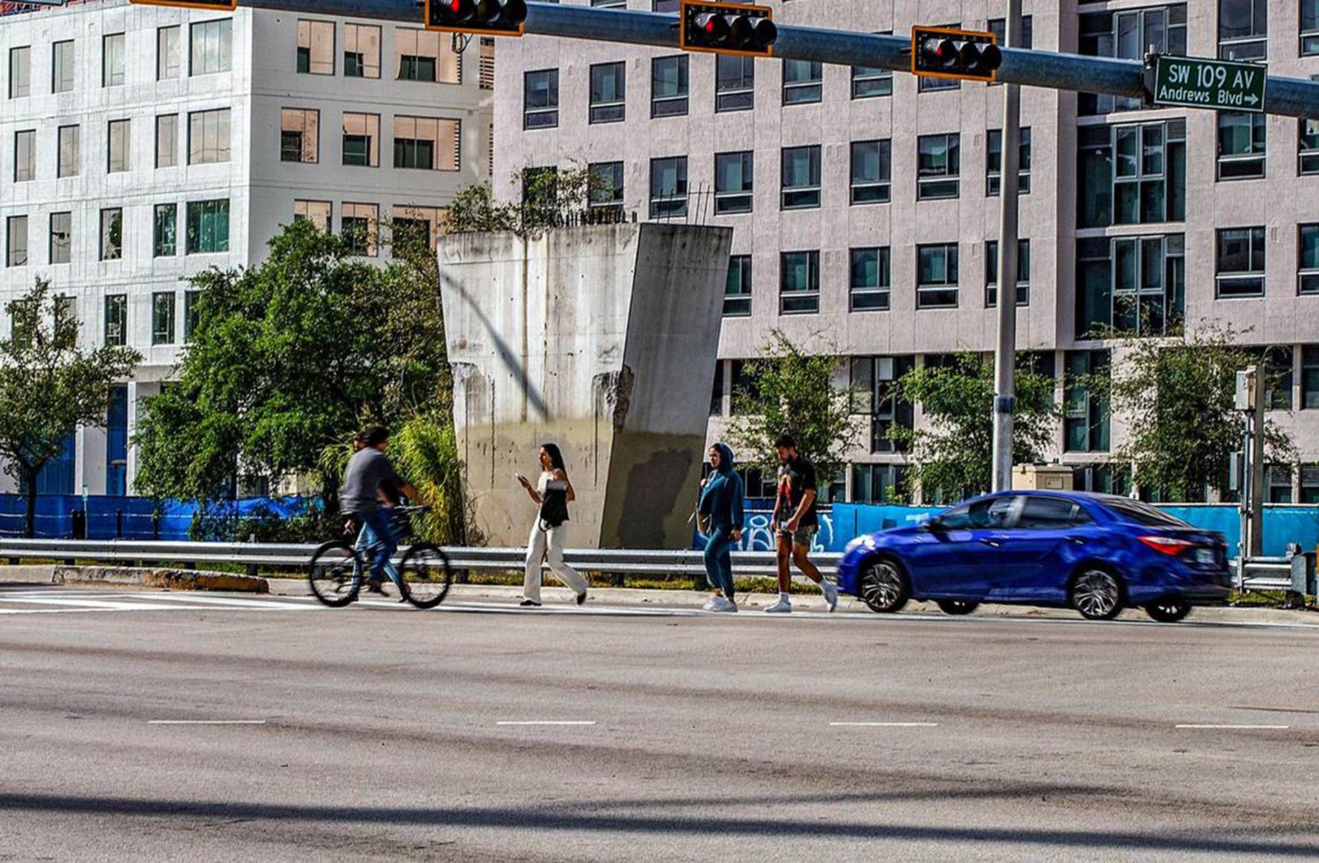 Students cross Southwest Eighth Street in front of a support pylon left in place after a pedestrian bridge collapsed while under construction across the busy road in 2018. The column, on the north side of the road at 109th Avenue, will be demolished once construction starts in early 2024 on a proposed new bridge linking Sweetwater's residential University City district, seen in the background, and Florida International University's man campus. (Pedro Portal/Miami Herald/Tribune News Service via Getty Images)