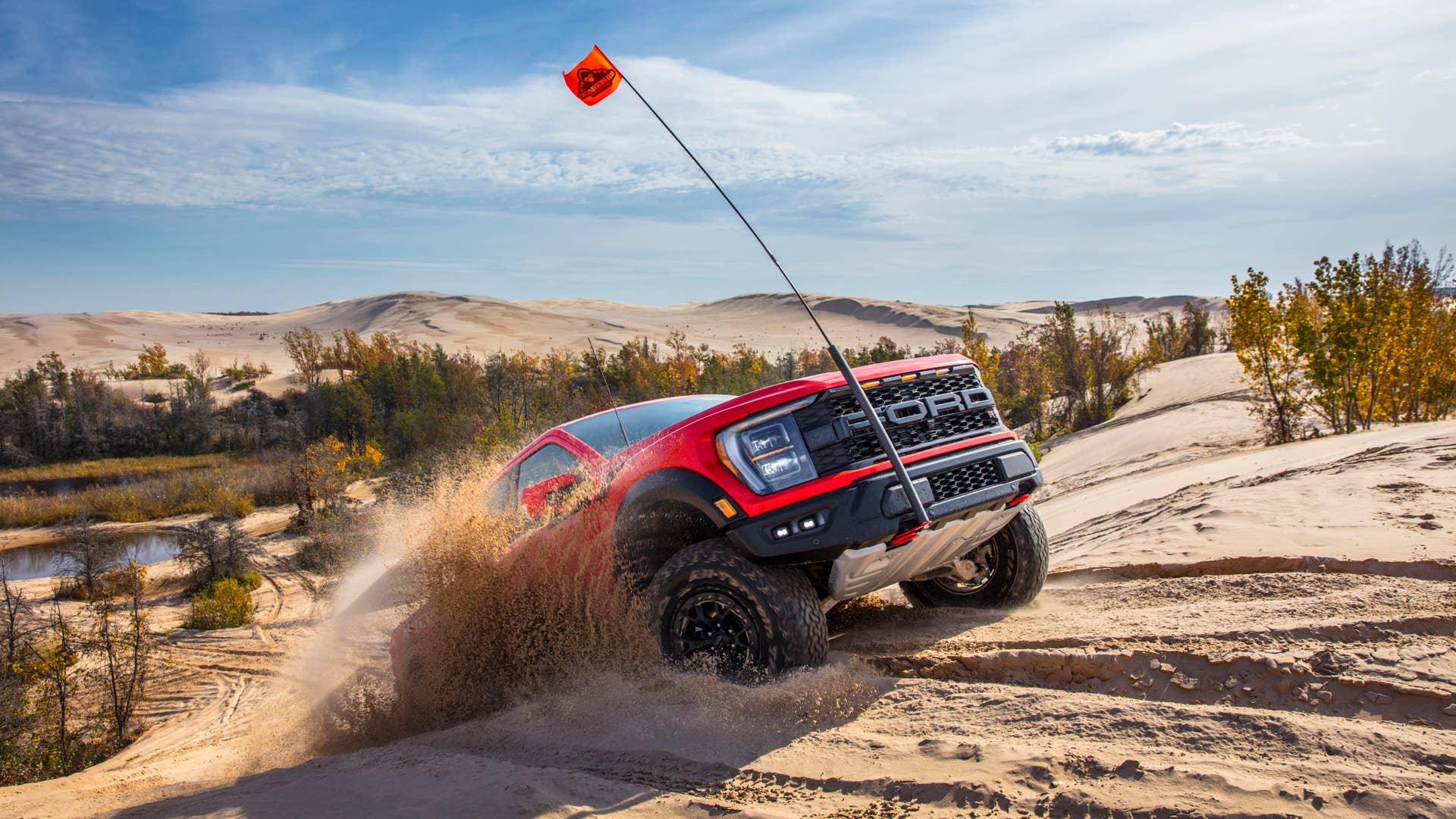 Preproduction 2023 F-150 Raptor R with aftermarket flag and optional equipment. Available late 2022. Professional driver on a closed course. Always consult the Raptor supplement to the Owner’s Manual before off-road driving, know your terrain and trail difficulty, and use appropriate safety gear.