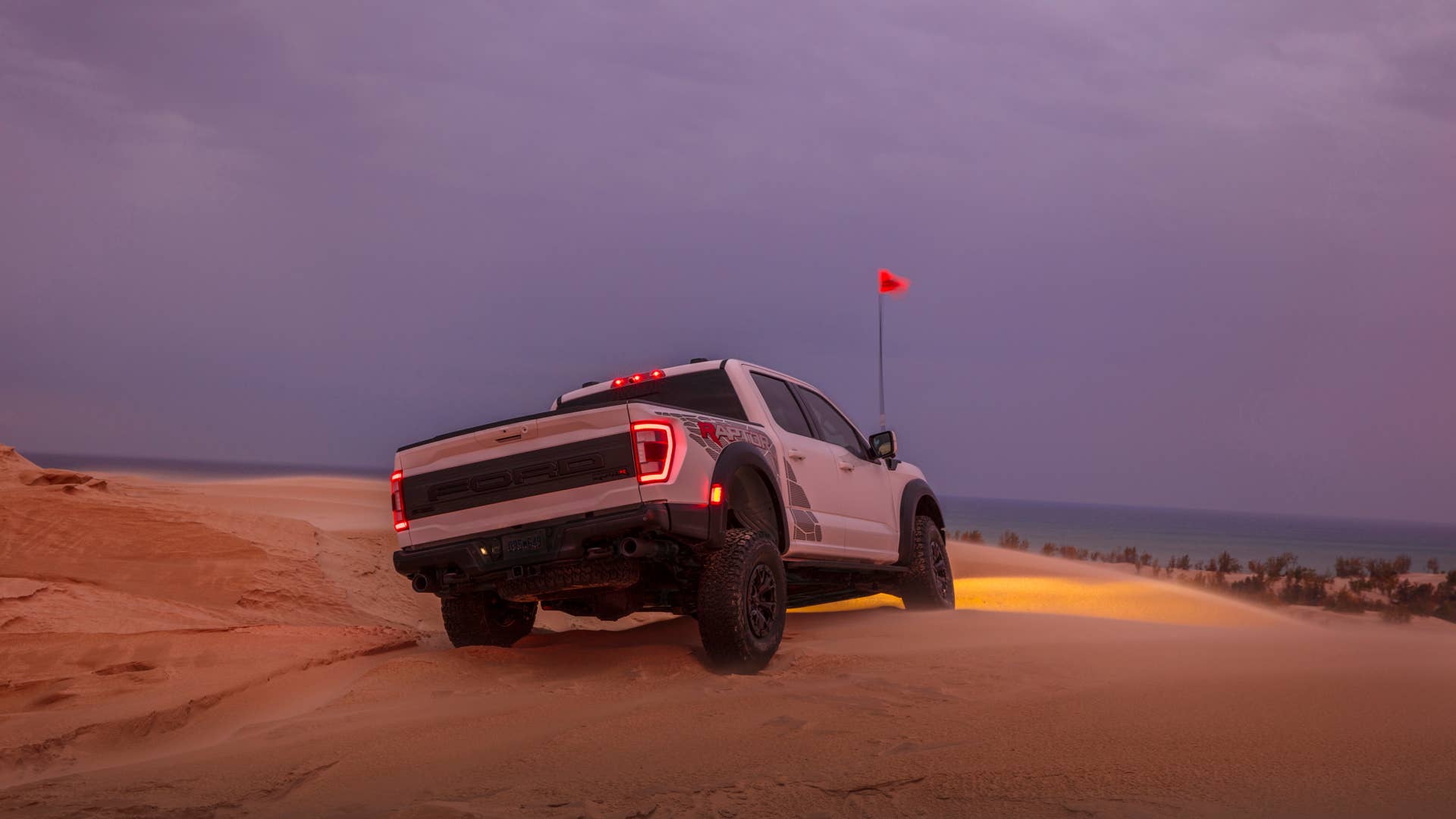 Preproduction 2023 F-150 Raptor R with aftermarket flag and optional equipment. Available late 2022. Professional driver on a closed course. Always consult the Raptor supplement to the Owner’s Manual before off-road driving, know your terrain and trail difficulty, and use appropriate safety gear.