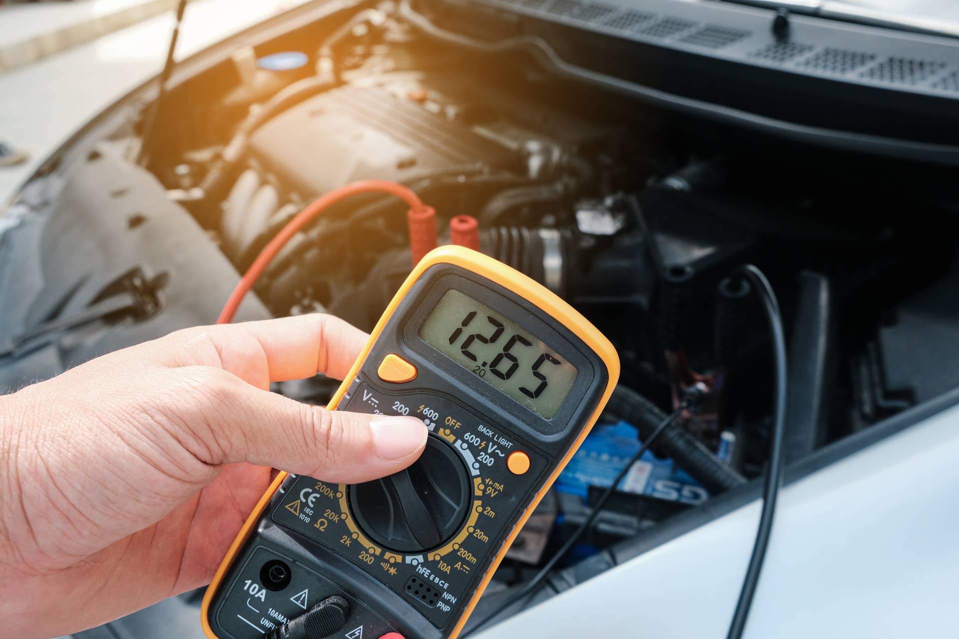 Mechanic hand use multimeter voltmeter to check the voltage level in a car battery.