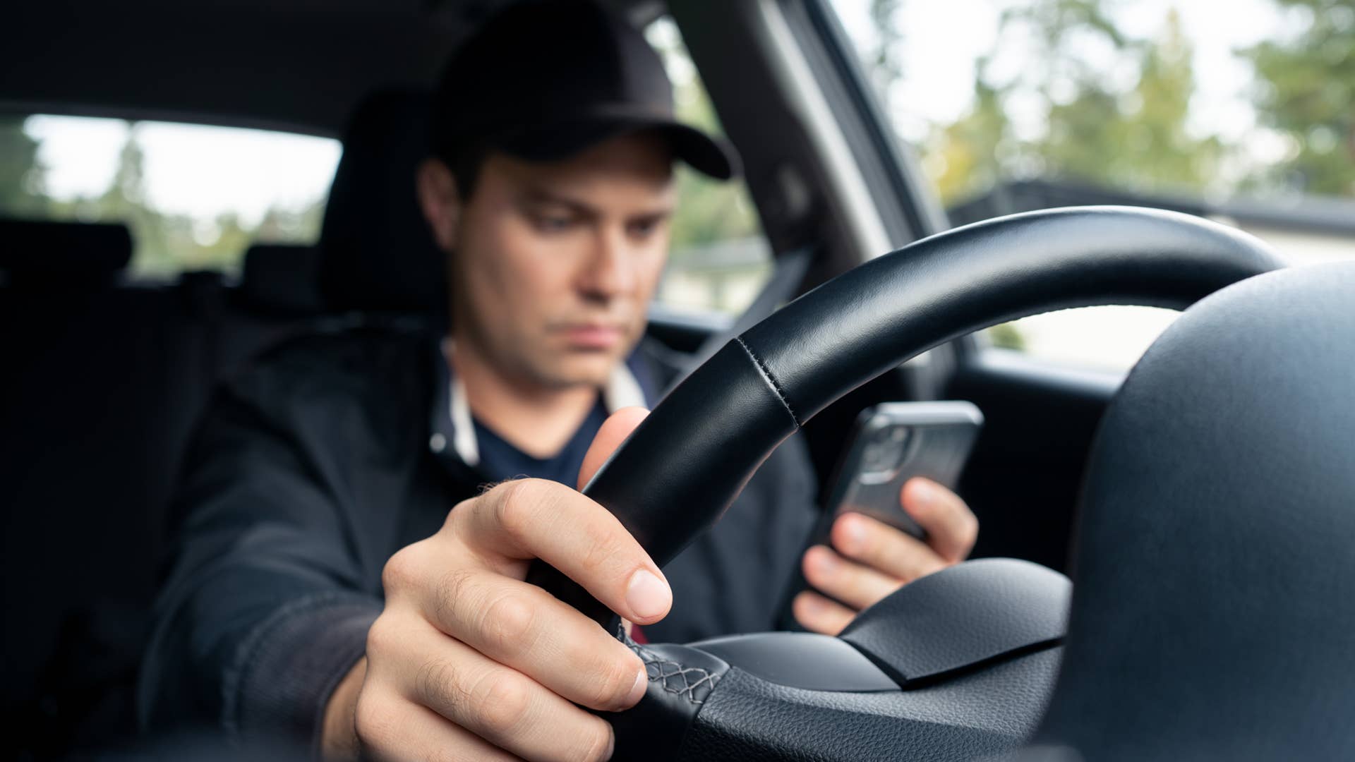 Driving car and using phone to text. Driver using cellphone. Accident, crash and danger in traffic. Man texting with mobile app. Distracted by mobilephone. Checking sms message with smartphone.