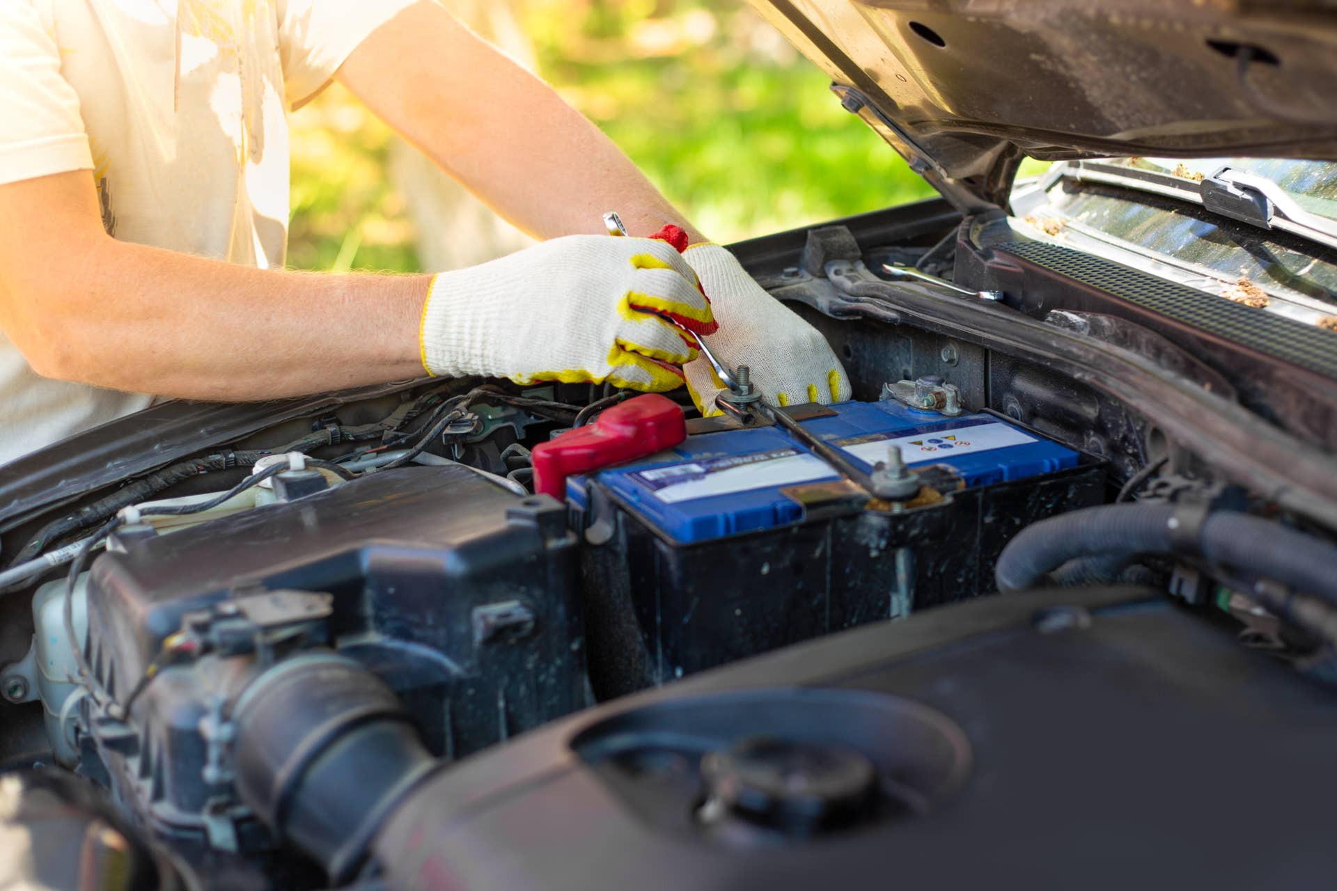 A man unscrews a car battery mount. Battery repair and replacement.