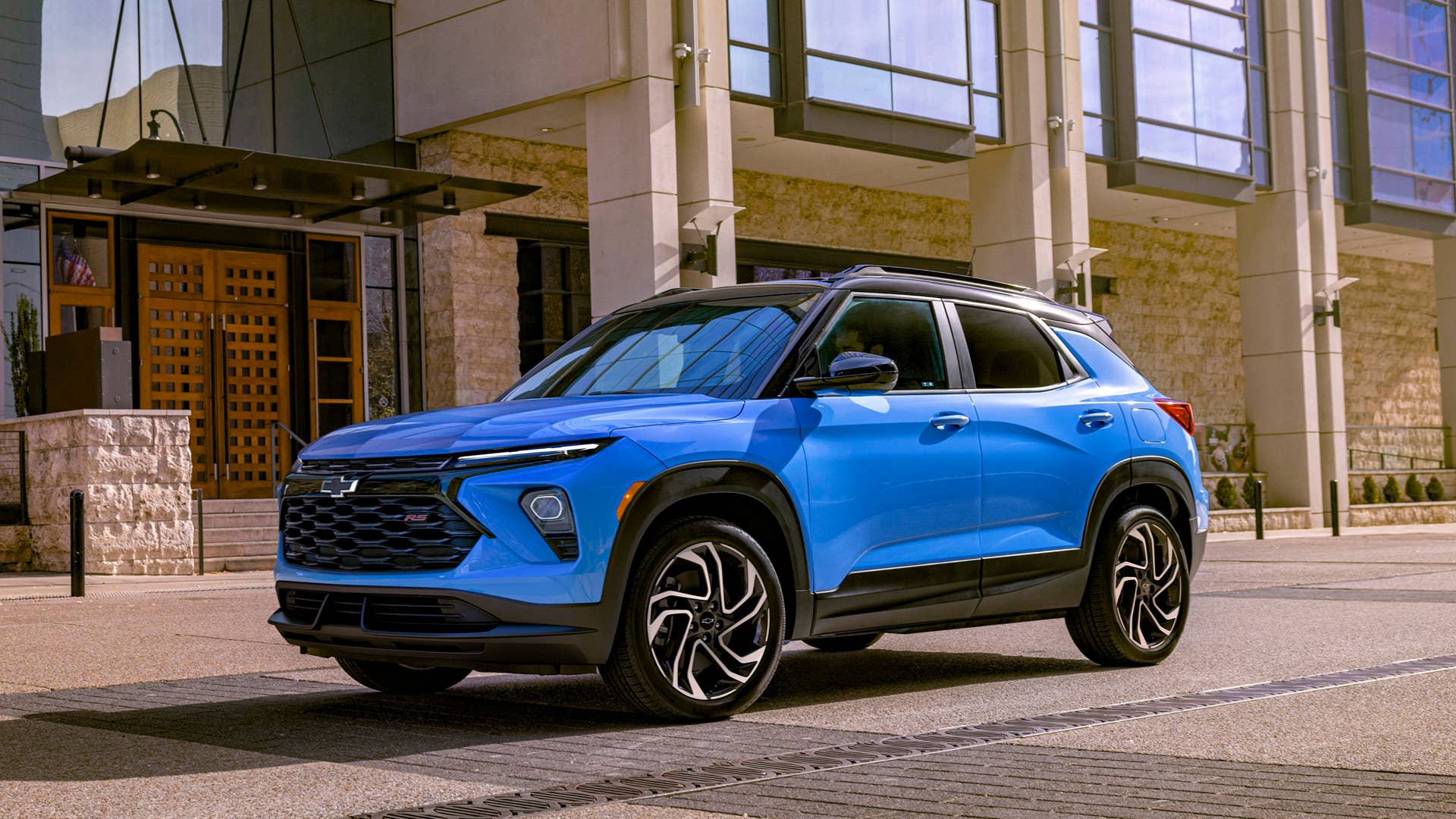 Driver’s side front 3/4 view of 2024 Chevrolet Trailblazer RS in Fountain Blue driving past a building. Preproduction model shown. Actual production model may vary. Available in fall 2023.