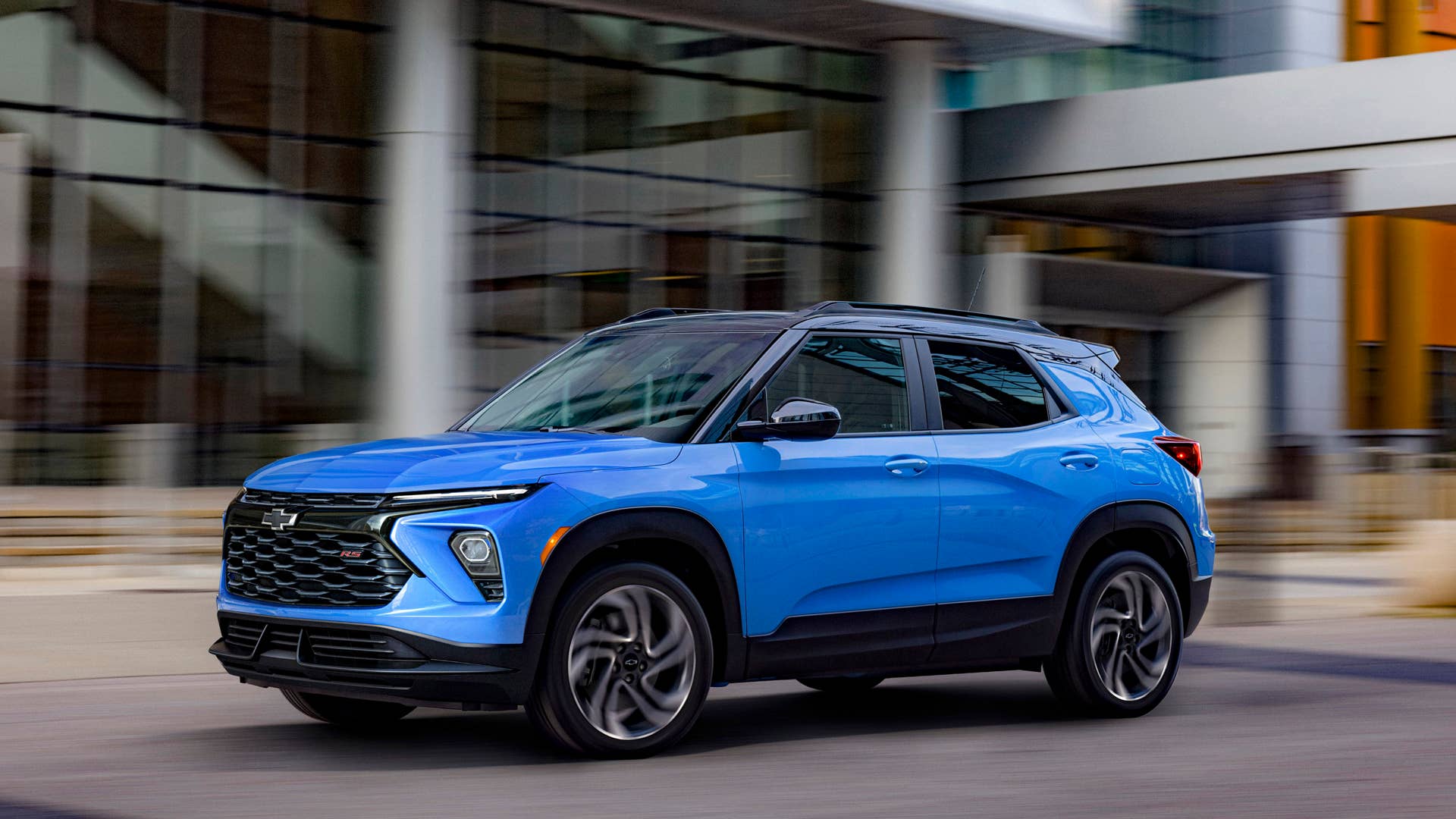 Driver’s side front 3/4 view of 2024 Chevrolet Trailblazer RS in Fountain Blue driving past a building. Preproduction model shown. Actual production model may vary. Available in fall 2023.