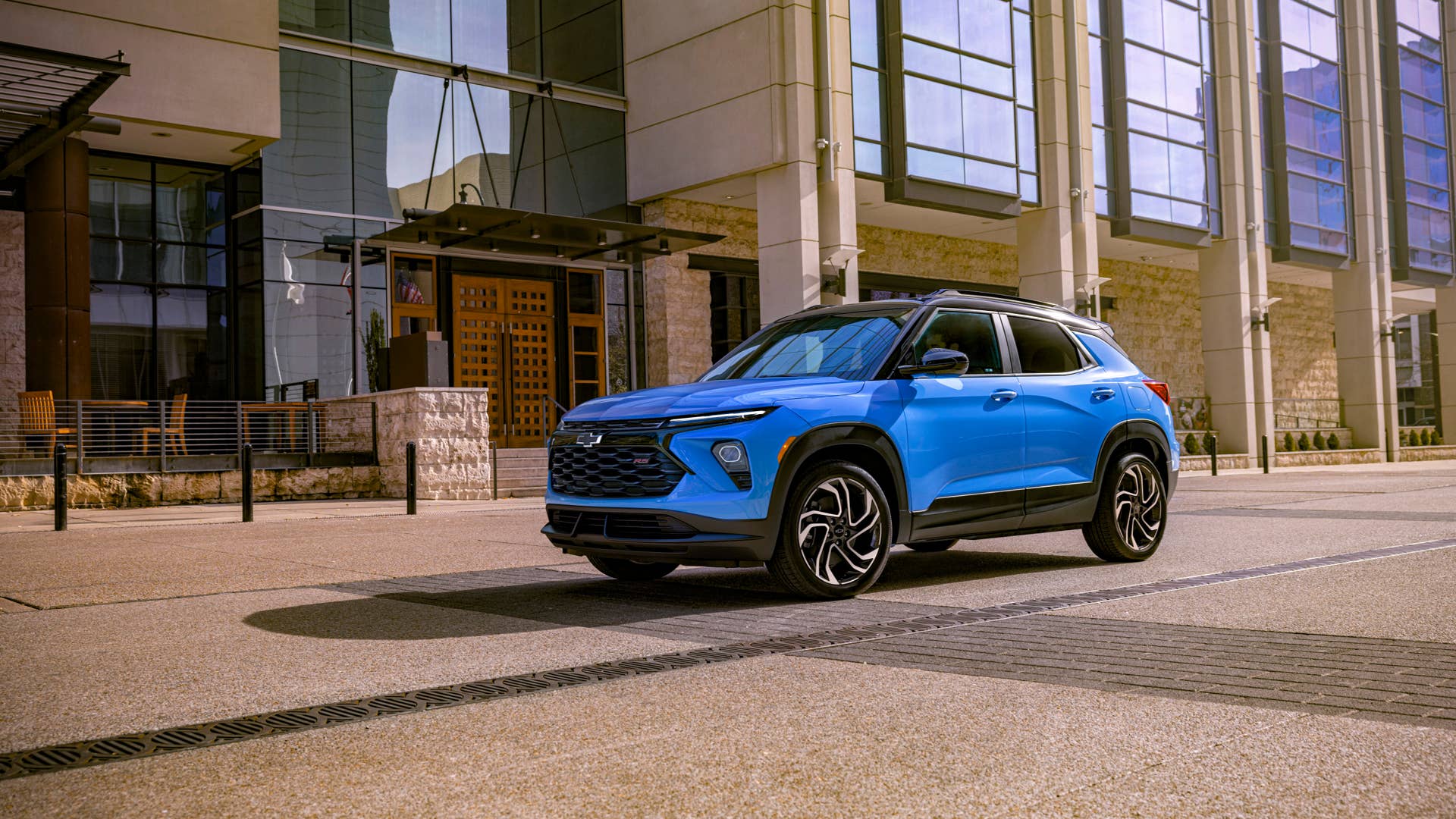 Driver’s side front 3/4 view of 2024 Chevrolet Trailblazer RS in Fountain Blue driving past a building. Preproduction model shown. Actual production model may vary. Available in fall 2023.