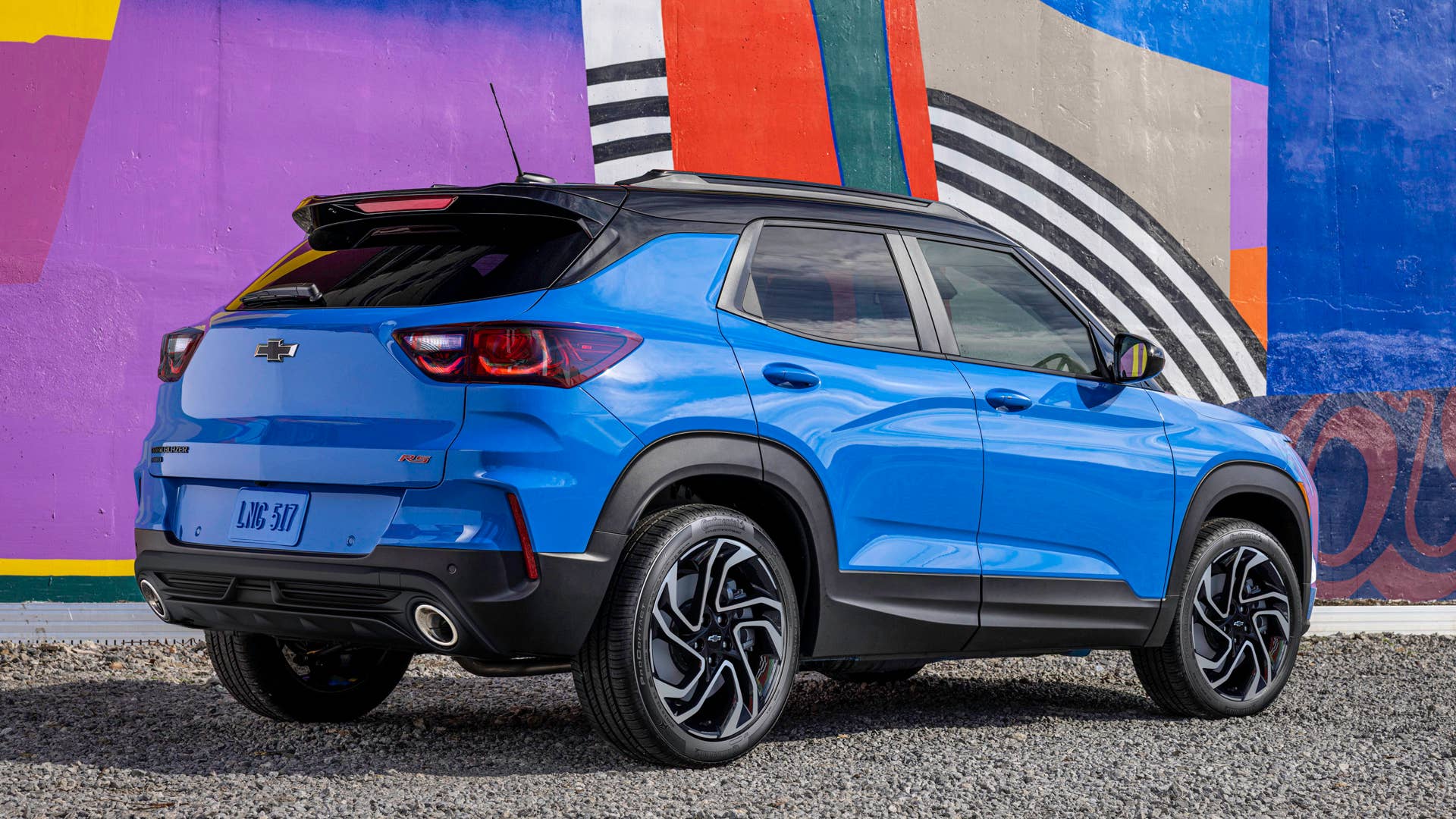 Rear 3/4 view of 2024 Chevrolet Trailblazer RS in Fountain Blue driving past a building. Preproduction model shown. Actual production model may vary. Available in fall 2023.