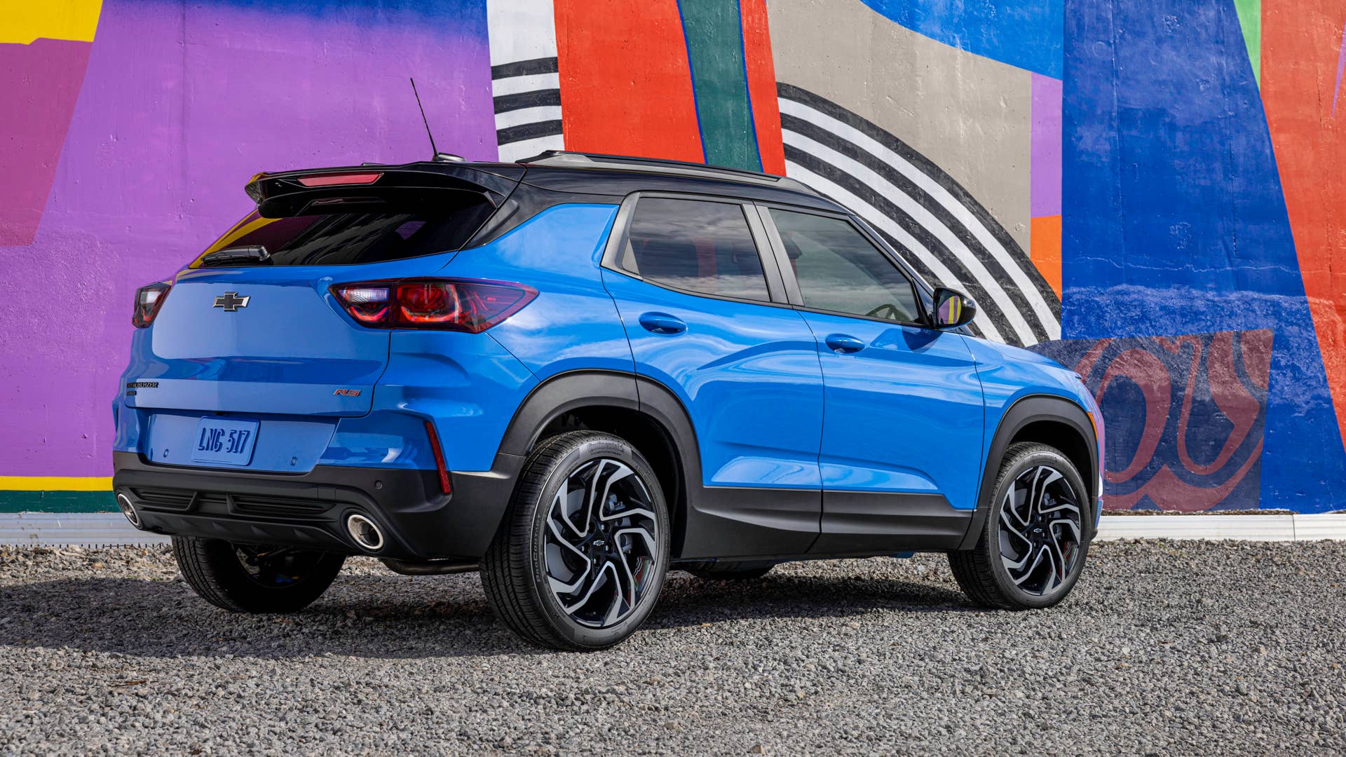 Rear 3/4 view of 2024 Chevrolet Trailblazer RS in Fountain Blue driving past a building. Preproduction model shown. Actual production model may vary. Available in fall 2023.