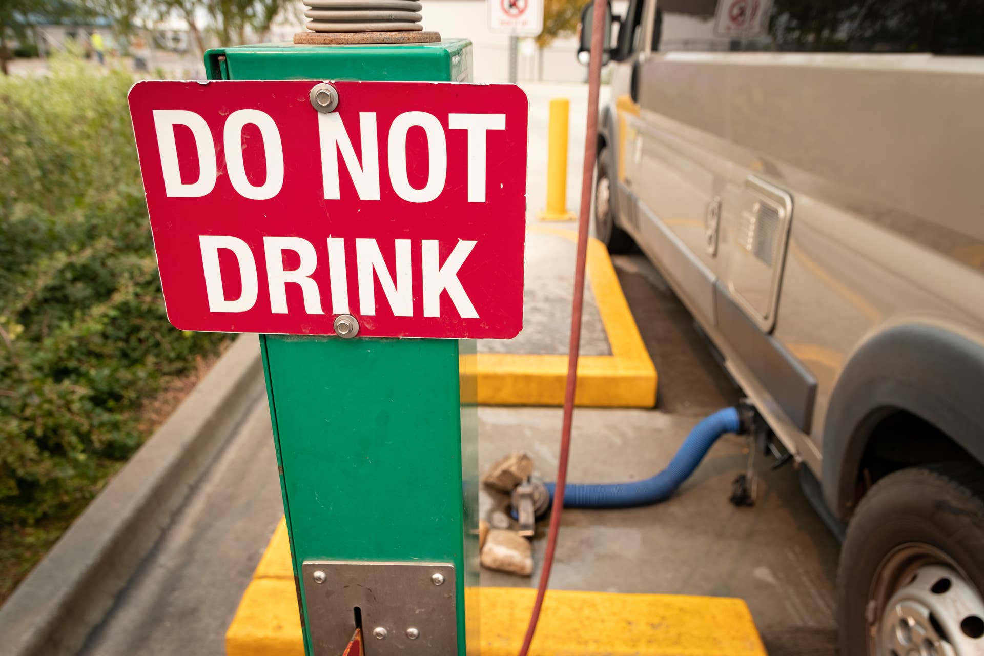 "DO NOT DRINK" sign at RV wastewater dumping station; RV connected and dumping in view