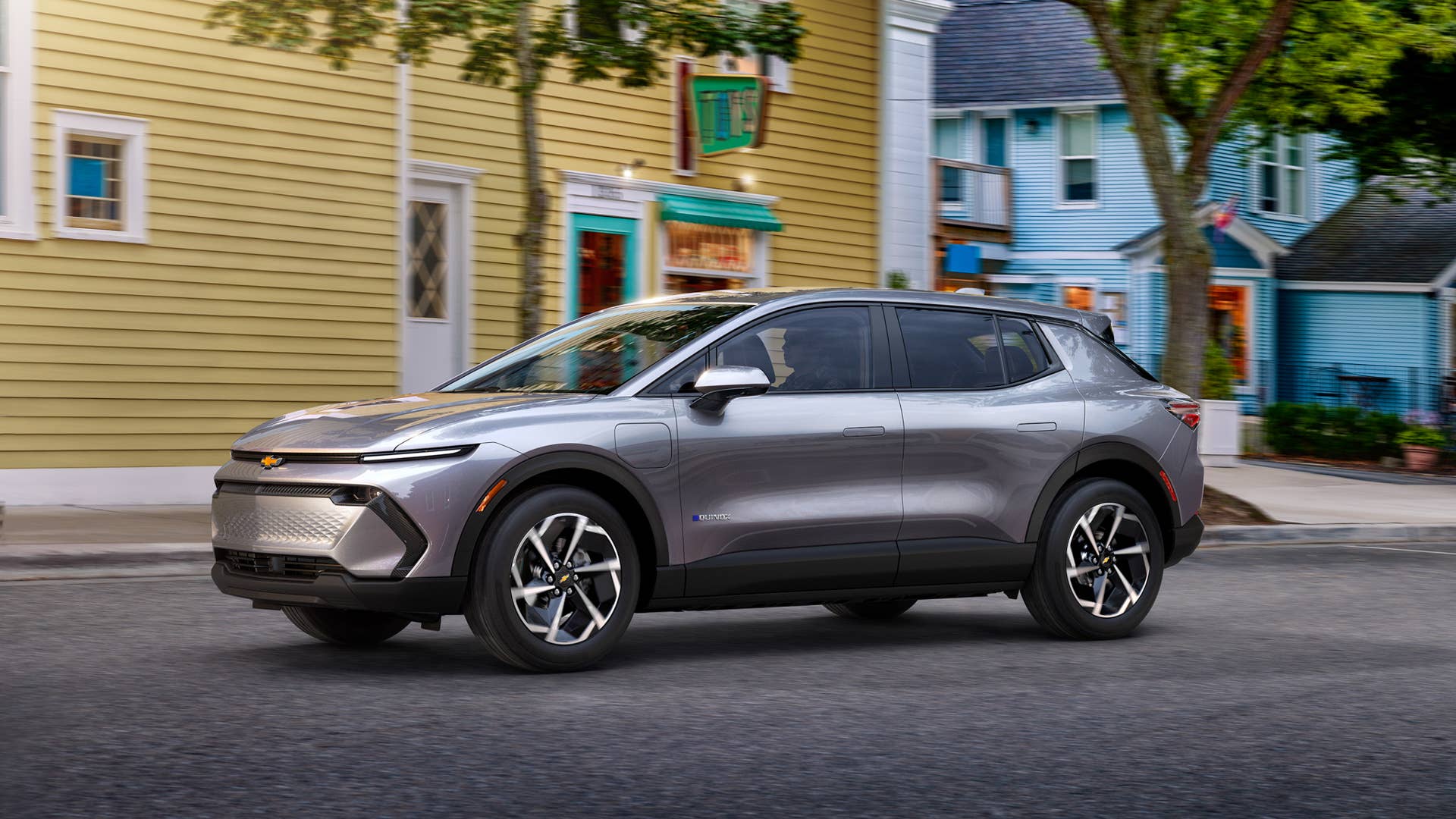 Driver’s side view of 2024 Chevrolet Equinox EV 1LT in Galaxy Gray Metallic driving down a road. Preproduction model shown. Actual production model may vary. 2024 Chevrolet Equinox EV available Fall 2023.