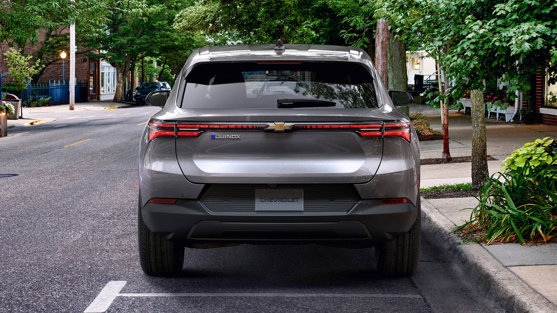Rear view of 2024 Chevrolet Equinox EV 1LT in Galaxy Gray Metallic parked on a street. Preproduction model shown. Actual production model may vary. 2024 Chevrolet Equinox EV available Fall 2023.