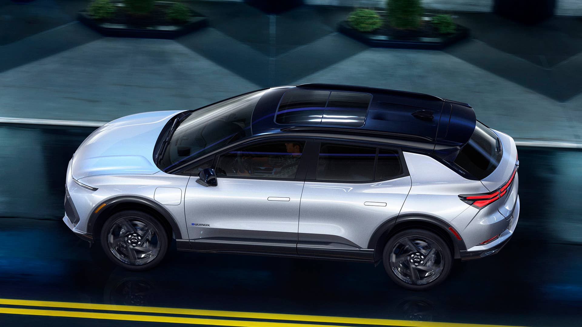 Overhead view of 2024 Chevrolet Equinox EV 3RS in Iridescent Pearl parked on city street at night. Preproduction model shown. Actual production model may vary. 2024 Chevrolet Equinox EV available Fall 2023.