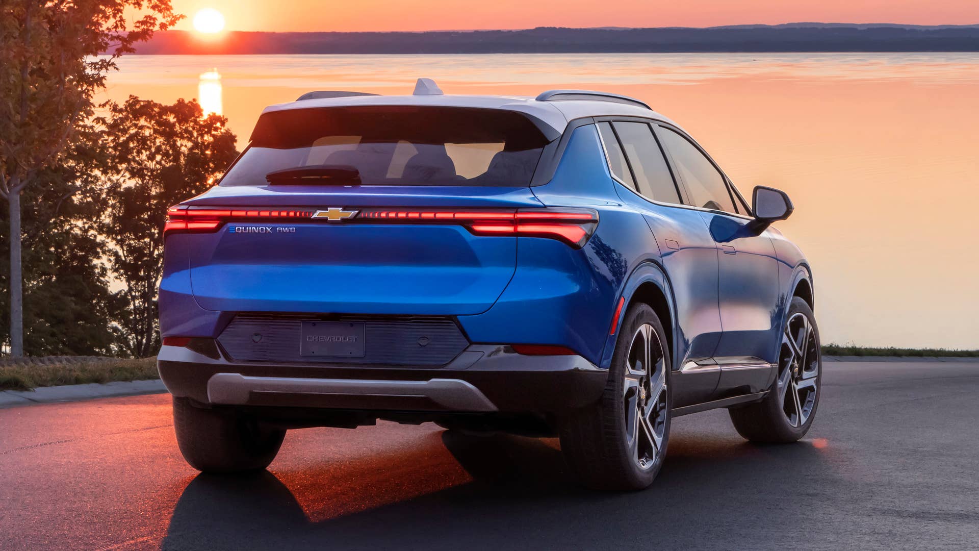Rear view of 2024 Chevrolet Equinox EV 3LT in Riptide Blue parked in front of sunset. Preproduction model shown. Actual production model may vary. 2024 Chevrolet Equinox EV available Fall 2023.