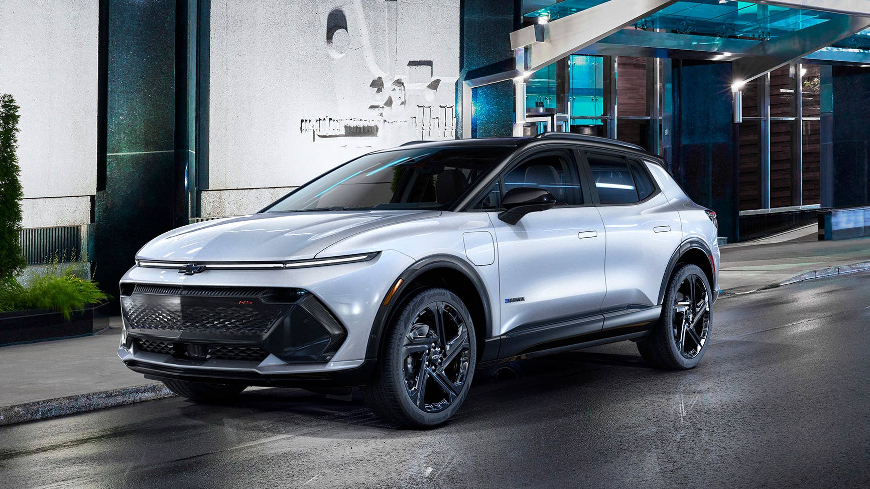 Driver’s side three-quarter view of 2024 Chevrolet Equinox EV 3RS in Iridescent Pearl parked on a city street at night. Preproduction model shown. Actual production model may vary. 2024 Chevrolet Equinox EV available Fall 2023.