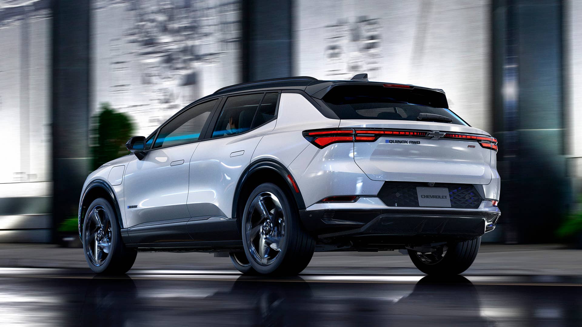 Rear three-quarter view of 2024 Chevrolet Equinox EV 3RS in Iridescent Pearl driving down a city street at night. Preproduction model shown. Actual production model may vary. 2024 Chevrolet Equinox EV available Fall 2023.