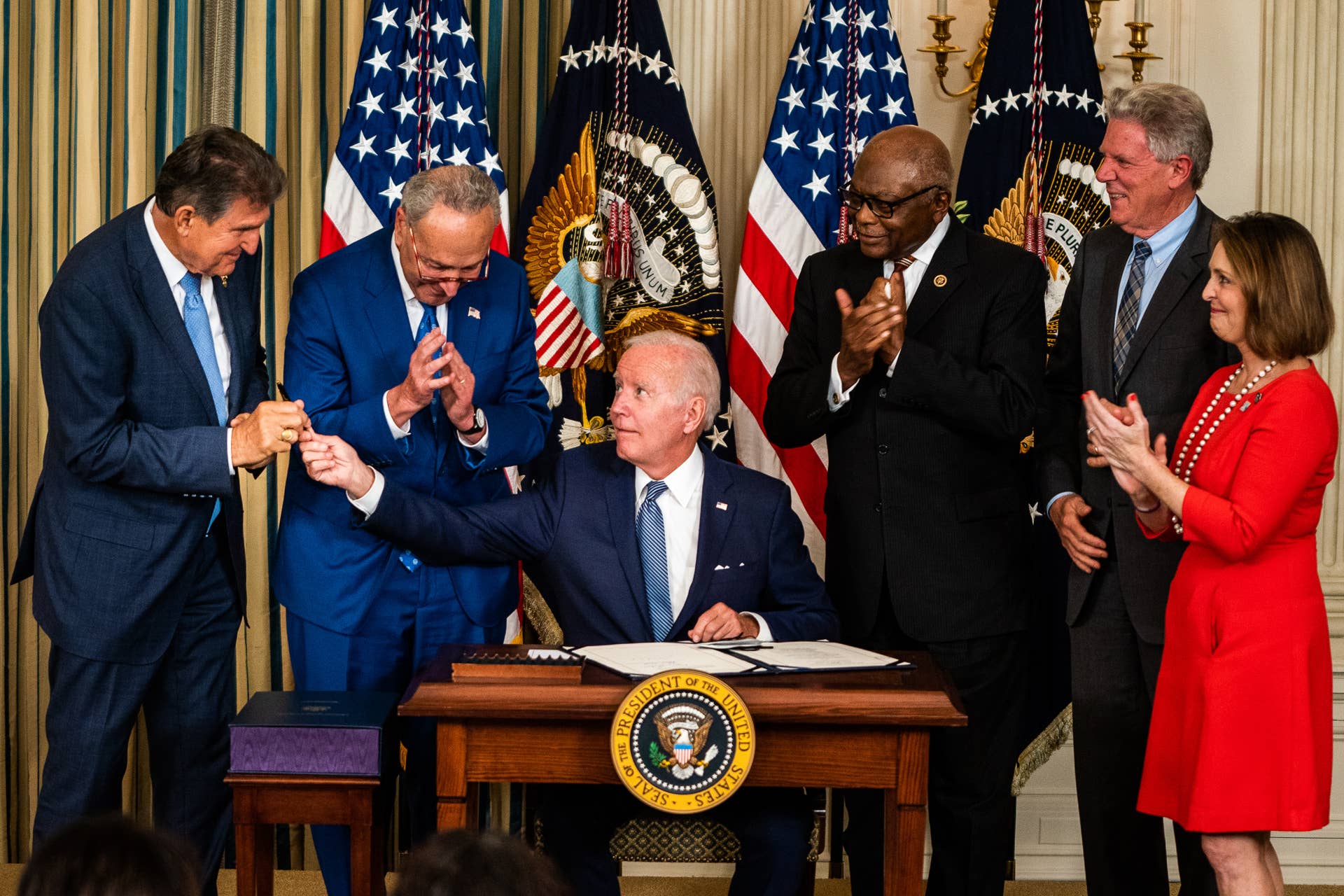 WASHINGTON, DC August 16, 2022:nnUS President Joe Biden hands Sen. Joe Manchin (D-W.VA) the pen used to sign into law H.R. 5376, the Inflation Reduction Act of 2022 (climate change and health care bill) in the State Dining Room of the White House on Tuesday August 16, 2022. From left, Sen. Joe Manchin (D-W.VA), Senate Majority Leader Chuck Schumer (D-NY), House Majority Whip Rep. James Clyburn (D-SC), Rep. Frank Pallone (D-NJ), and Rep. Kathy Castor (D-FL).n(Photo by Demetrius Freeman/The Washington Post via Getty Images)