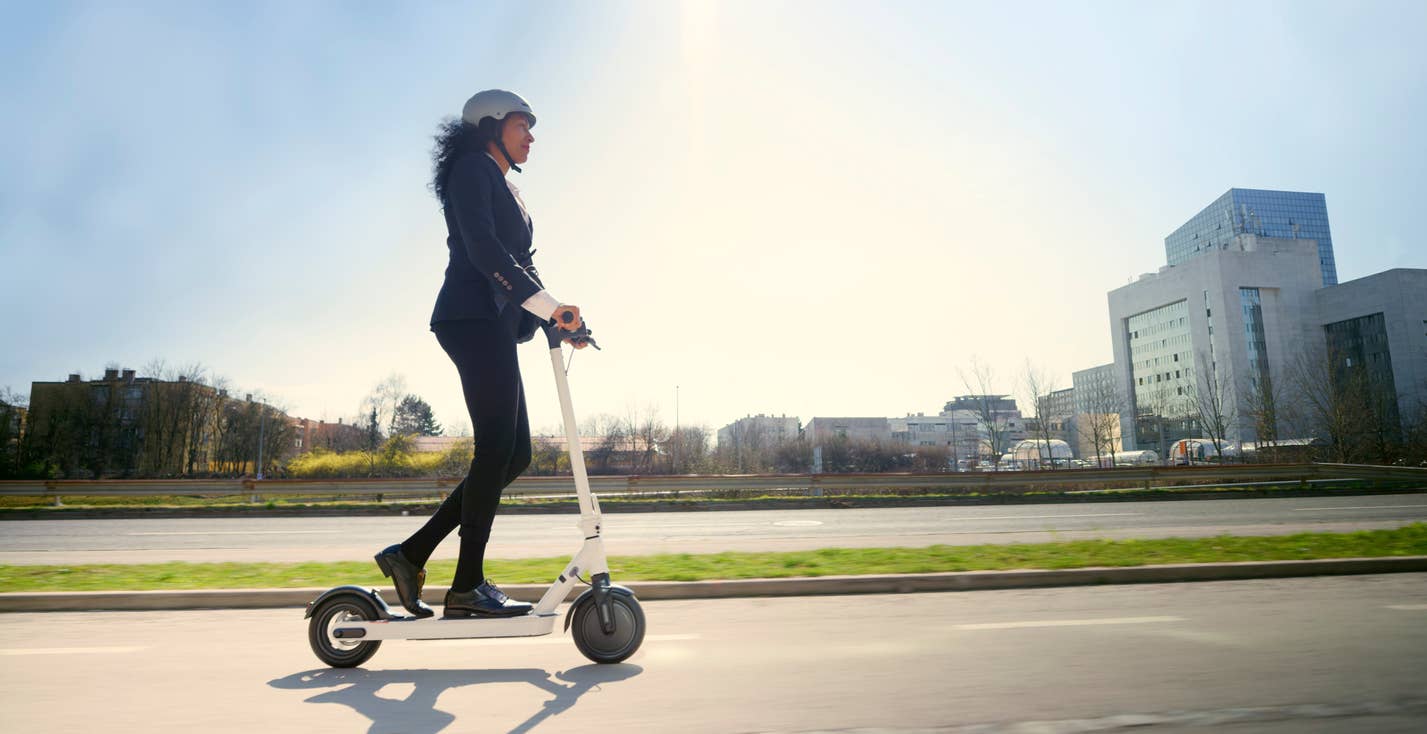 businesswoman riding electric push scooter in city