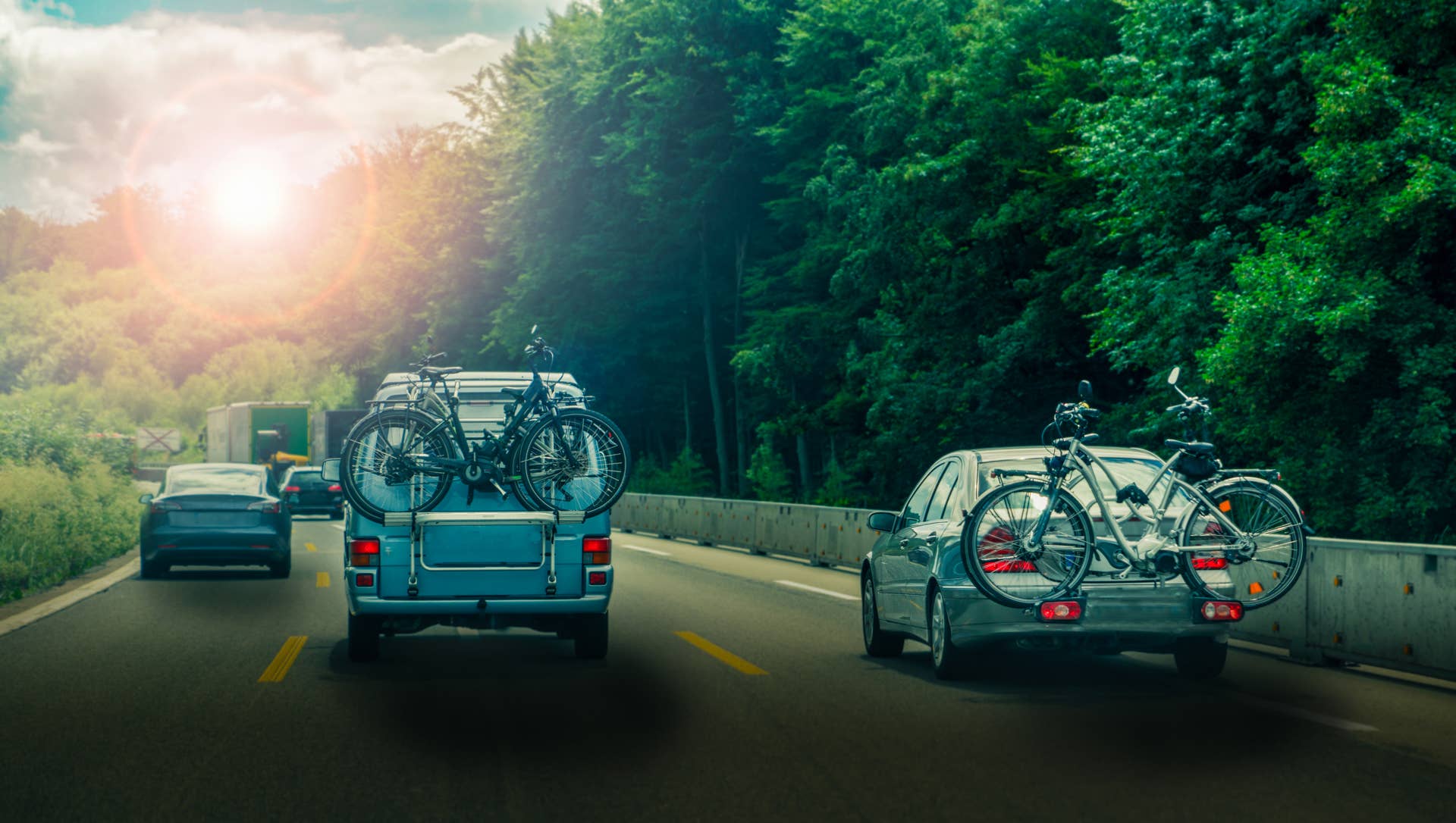 Car and minibus transport bicycles on a rack on highway in sunset