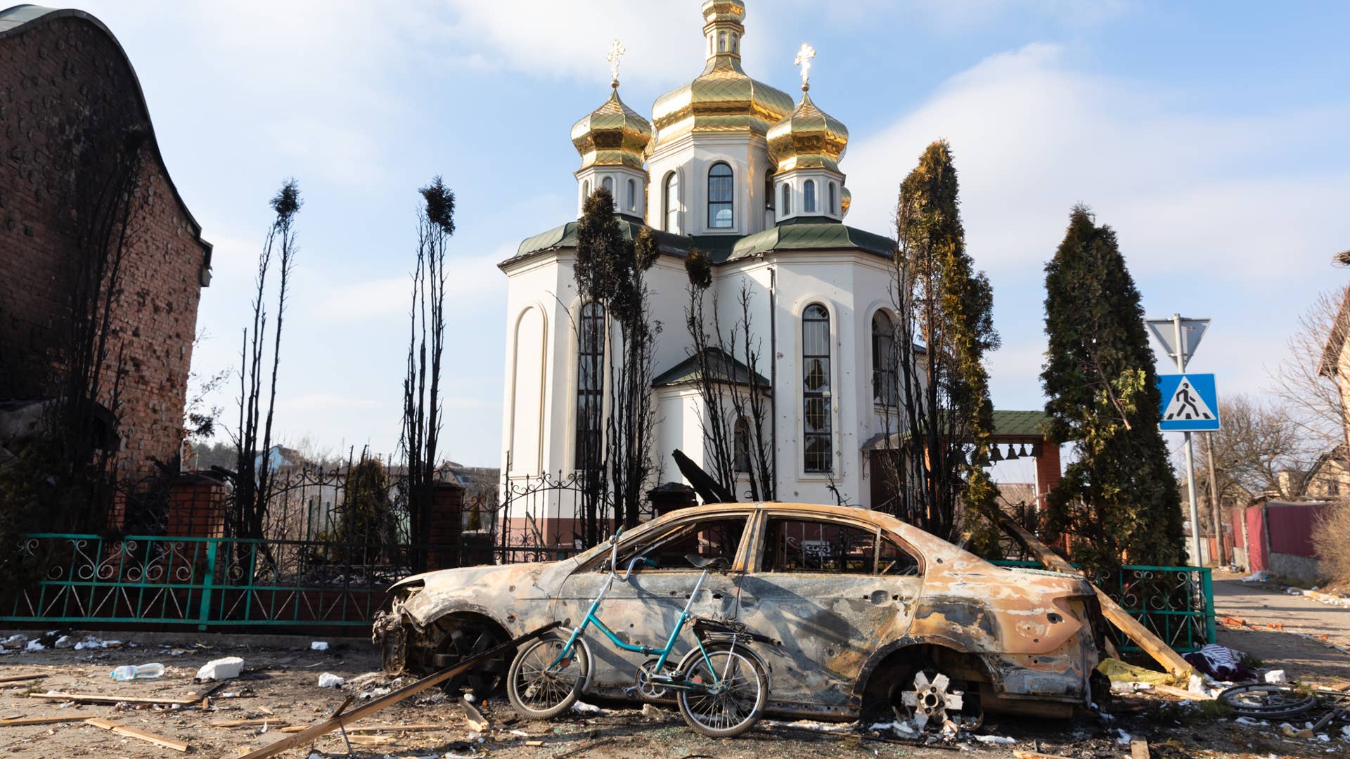 IRPIN, UKRAINE - Mar. 09, 2022: War in Ukraine. Chaos and devastation on the outskirts of Irpin. Damaged church and burned car as a result of the bombardment of a peaceful city