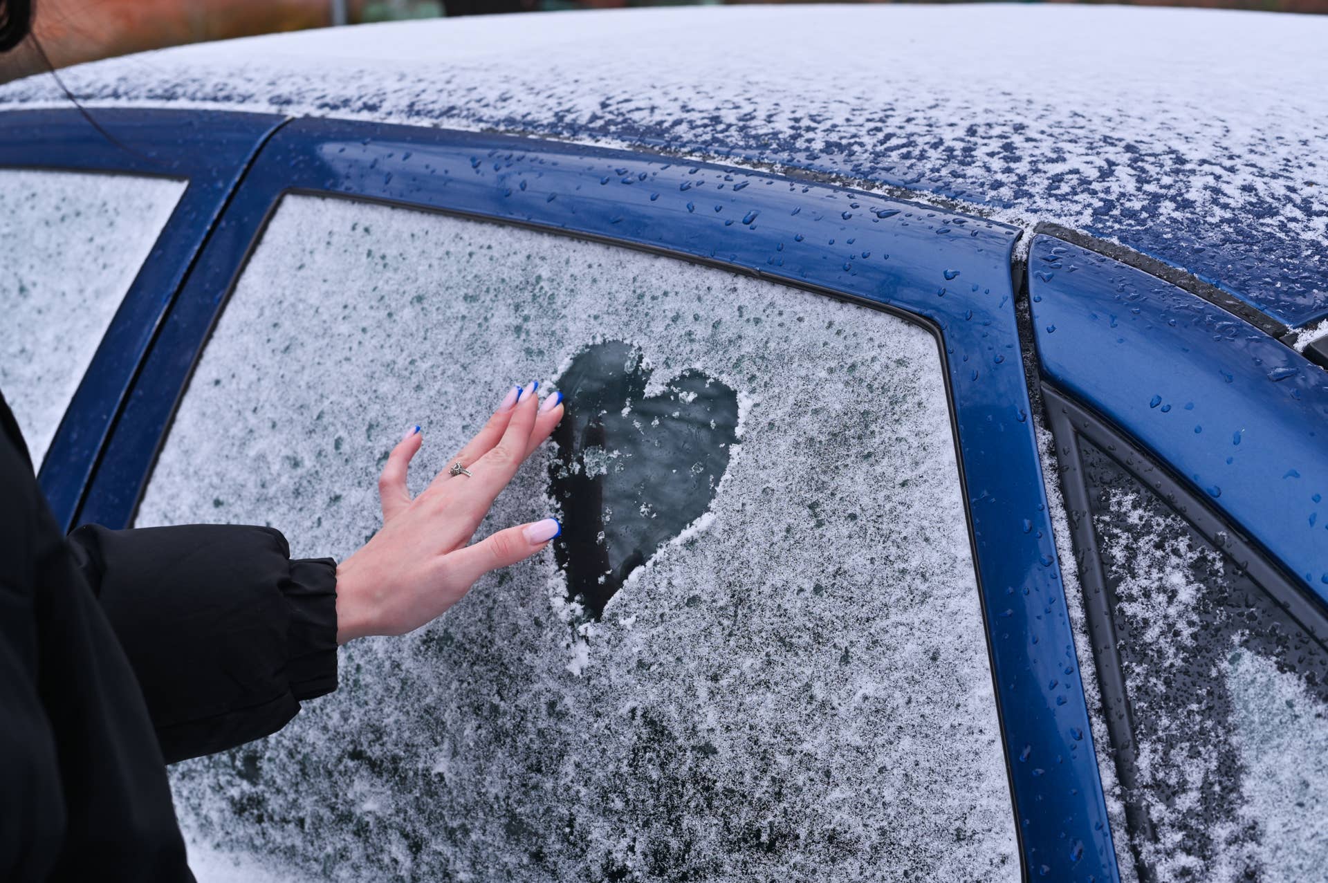 A woman draws heart on a car window