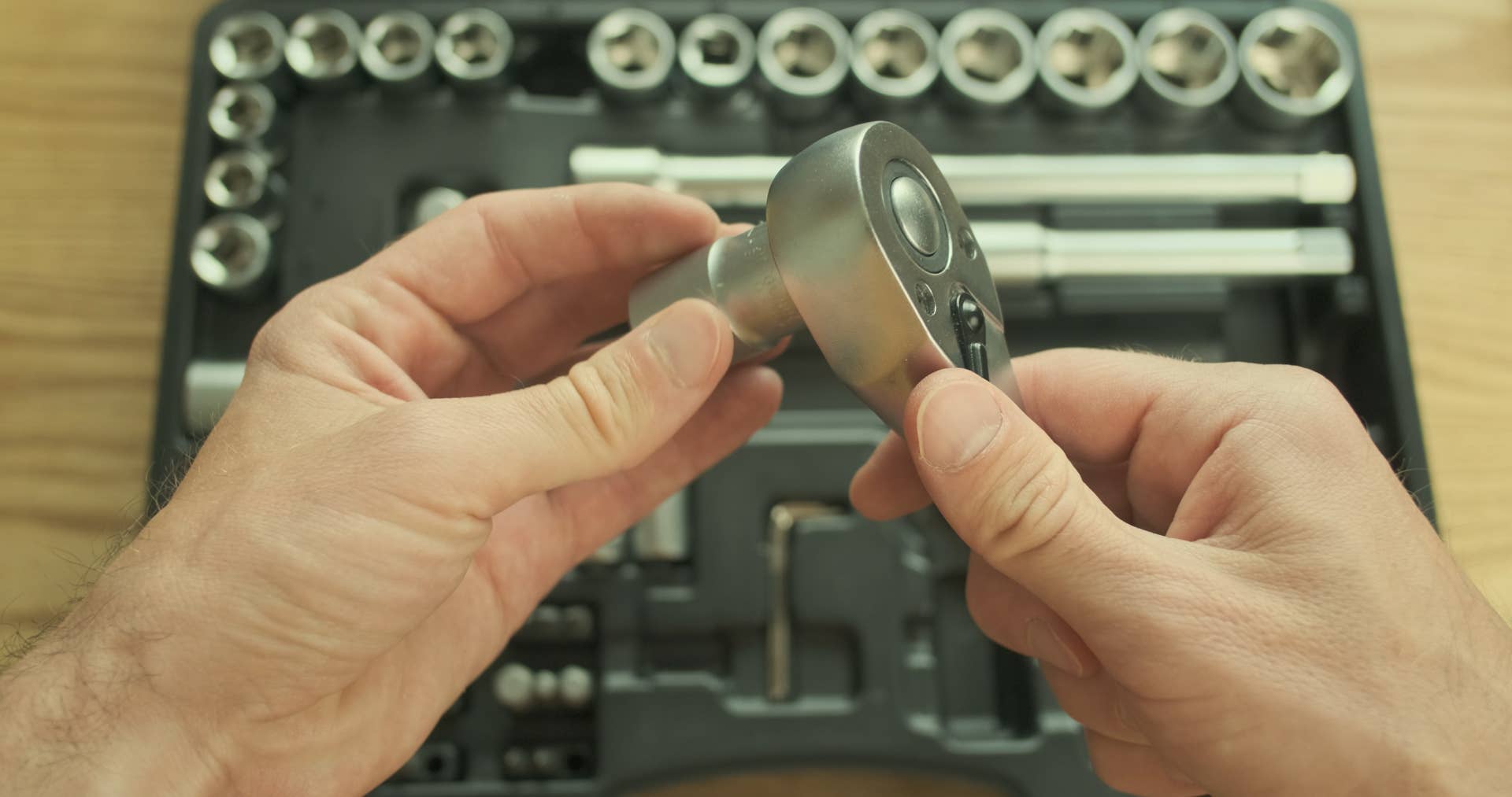Mechanic removes the head from the ratchet and puts everything in the toolbox on the table. Top view, close-up, first-person view. High quality photo