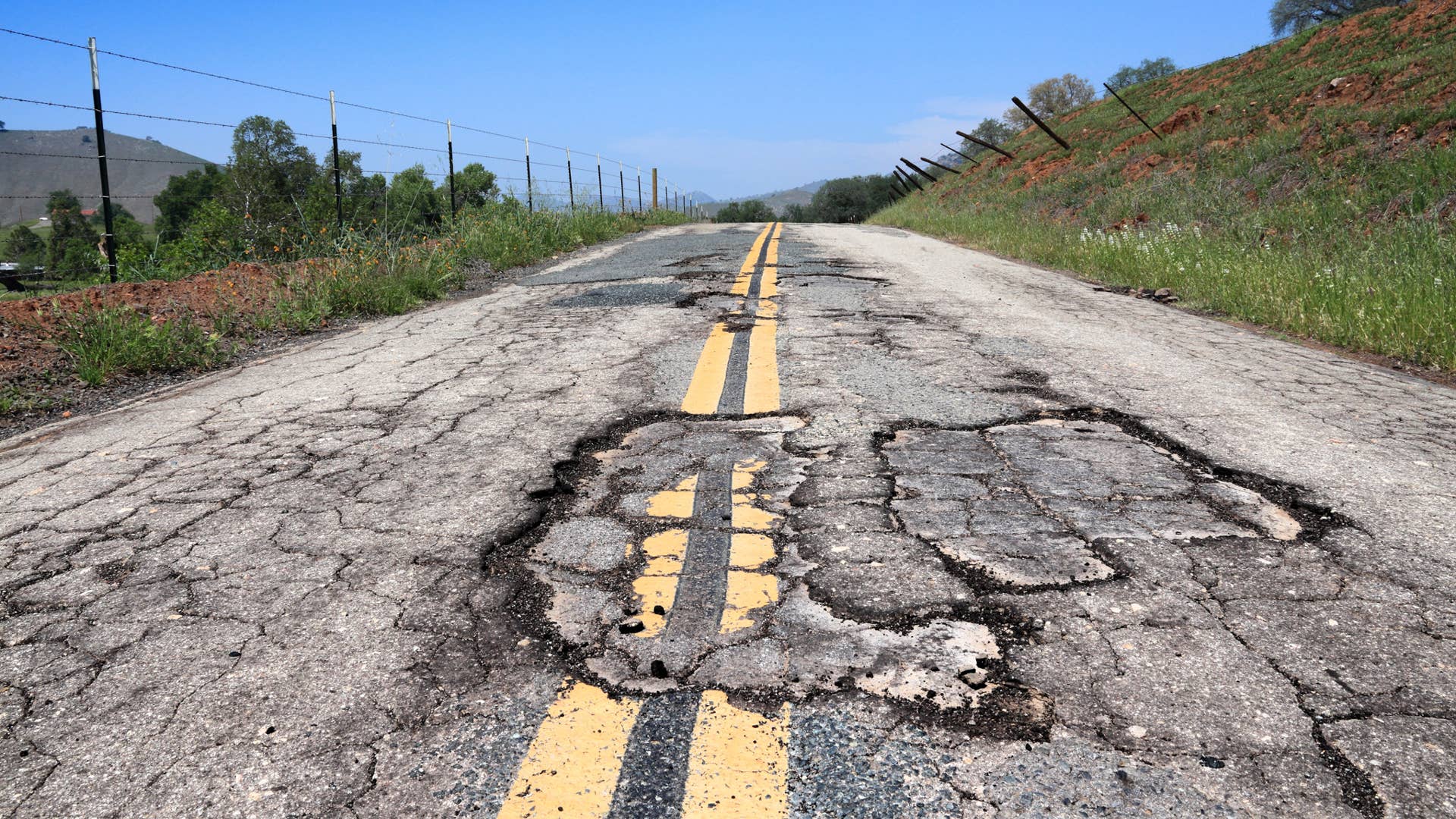 Pothole road - damaged rural road surface in California, USA.