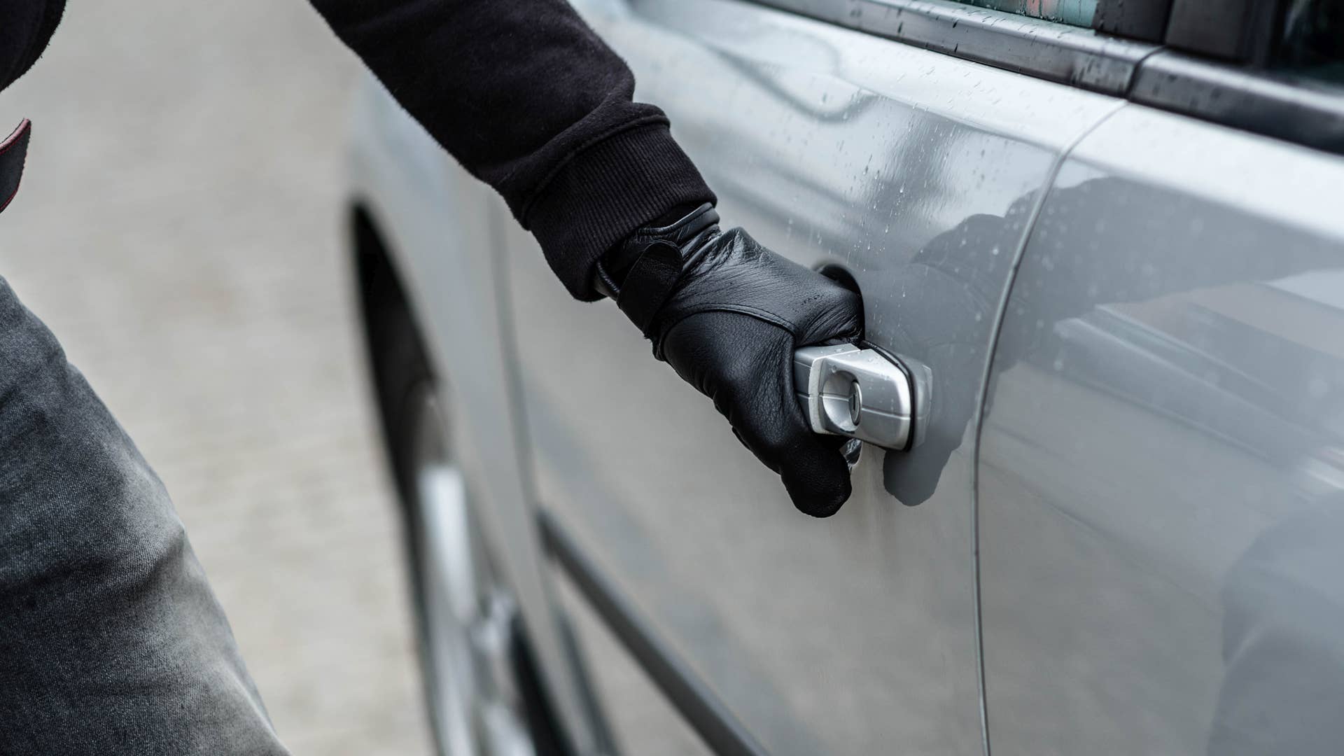 Close up on car thief hand pulling the handle of a car. Car thief, car theft concept