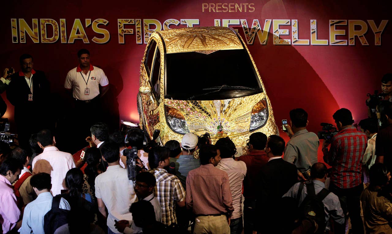 Journalists gather around the Tata Motors 'Nano' car which is crafted in gold, silver and gem stones during its unveiling in Mumbai, India, Monday ,Sept. 19, 2011. This version of the compact car, which was launched two years ago as the world's cheapest car in its original form, is claimed to be first gold jewelry car and made from 80 kilograms of 22 karat gold, 15 kilograms of silver, and numerous gemstones. (AP Photo/Rajanish Kakade)