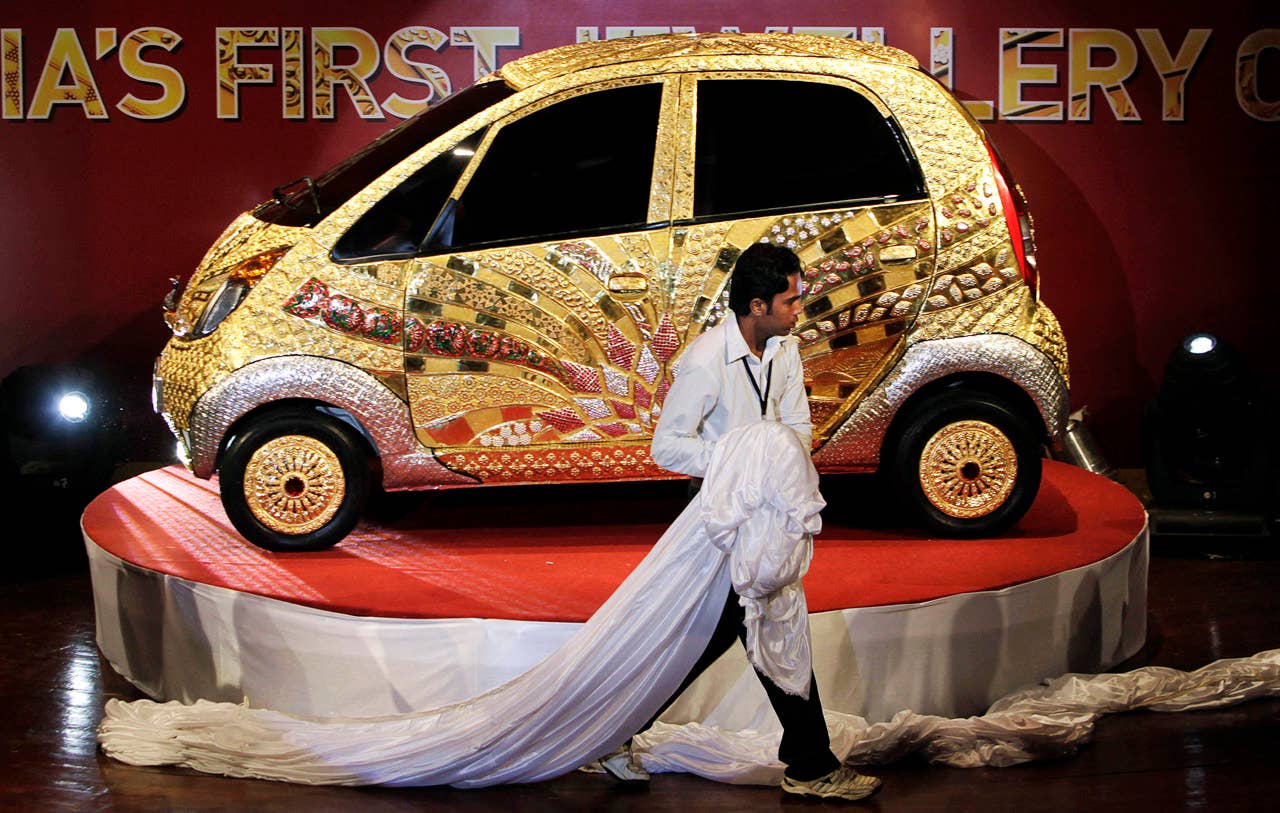 A worker removes a curtain on the Tata Motors 'Nano' car crafted in gold, silver and gem stones during its unveiling in Mumbai, India, Monday ,Sept. 19, 2011. This version of the compact car, which was launched two years ago as the world's cheapest car in its original form, is claimed to be first gold jewelry car and made from 80 kilograms of 22 karat gold, 15 kilograms of silver, and numerous gemstones. (AP Photo/Rajanish Kakade)