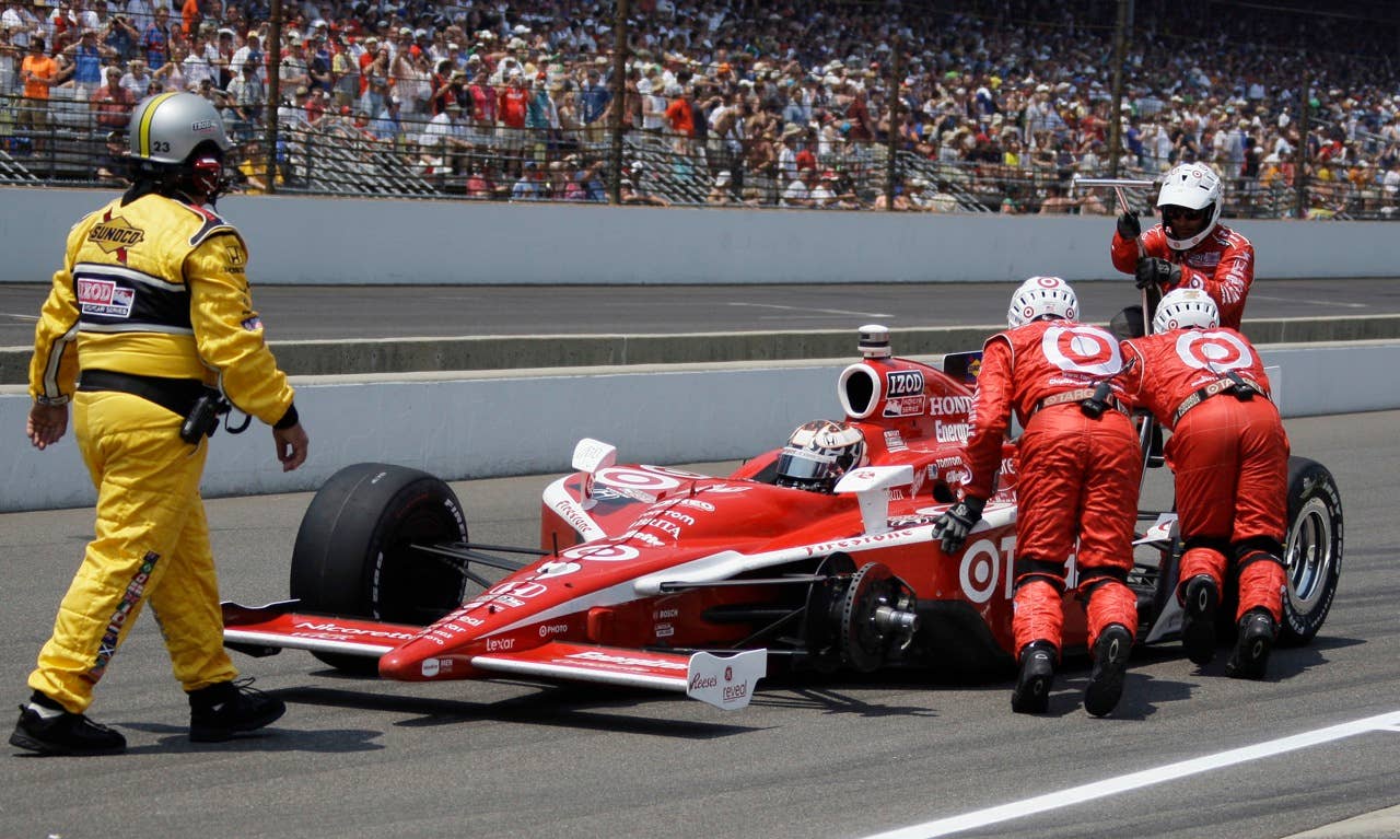 Pit crew members push Scott Dixon's car back after he lost a tire leaving the pits during the Indianapolis 500 auto race at the Indianapolis Motor Speedway in Indianapolis, Sunday, May 30, 2010. (AP Photo/Darron Cummings)