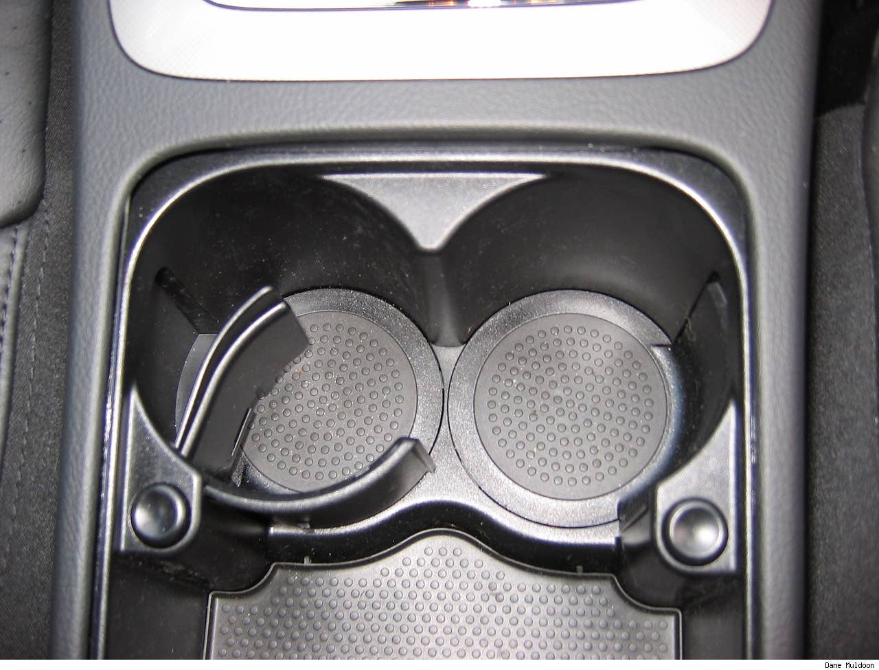 The centre console lid slides back to reveal a storage area with two retractable drink holders
