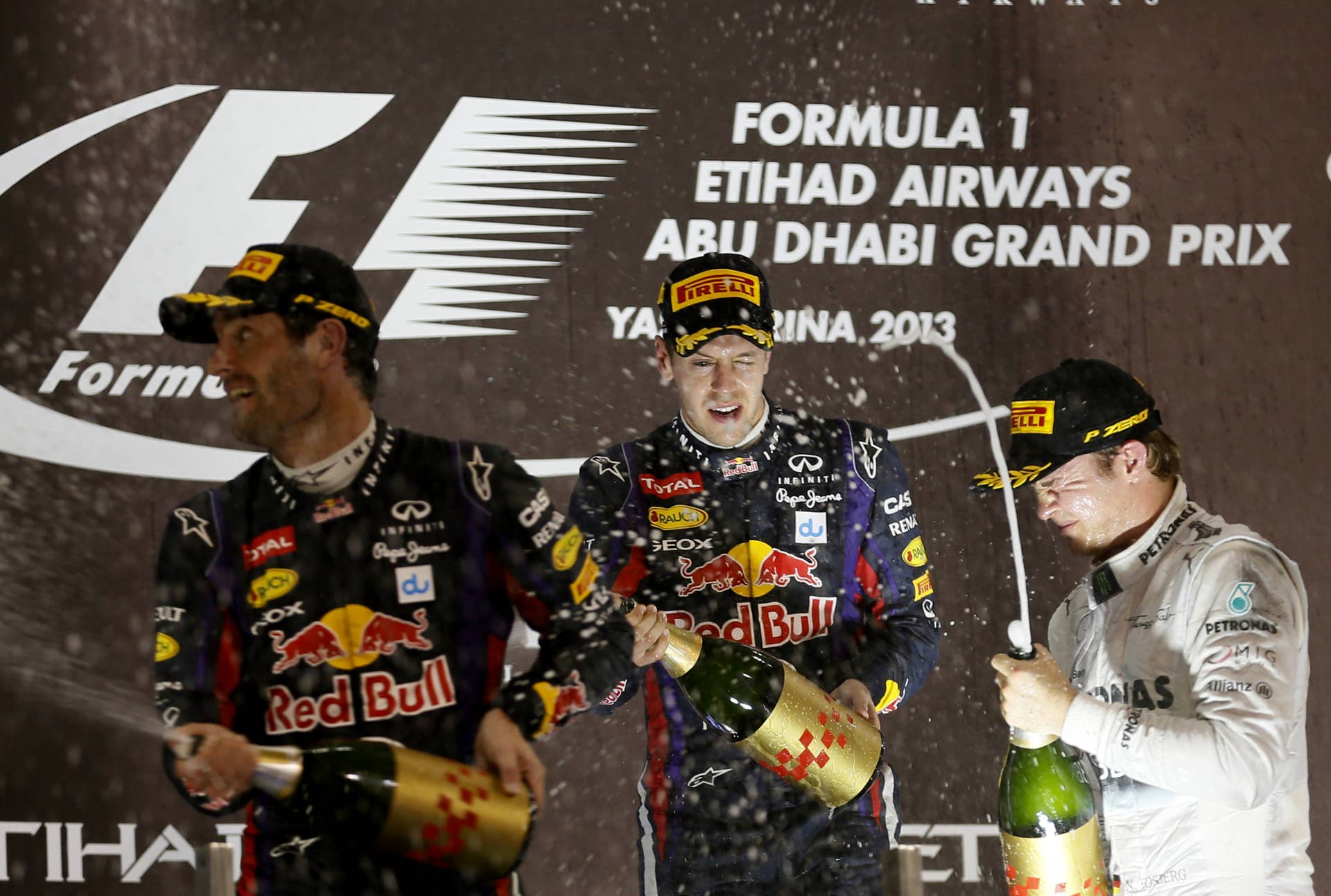 (L to R) Red Bull Racing's Australian driver Mark Webber, Red Bull Racing's German driver Sebastian Vettel and Mercedes'  German driver Nico Rosberg celebrate on the podium at the Yas Marina circuit in Abu Dhabi on November 3, 2013 after the Abu Dhabi Formula One Grand Prix.  AFP PHOTO / KARIM SAHIB        (Photo credit should read KARIM SAHIB/AFP/Getty Images)