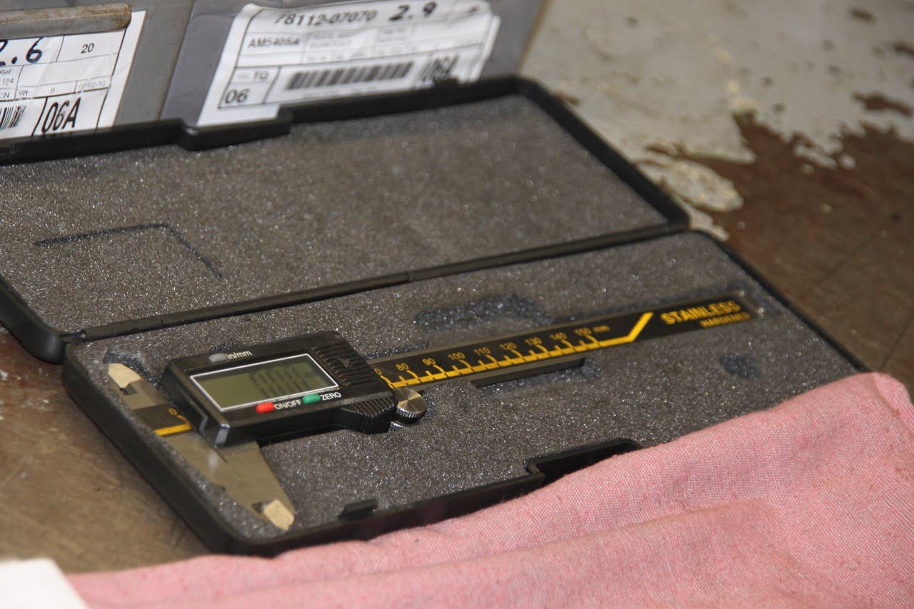 A digital caliper is used to check the thickness of the feeler gauge.
