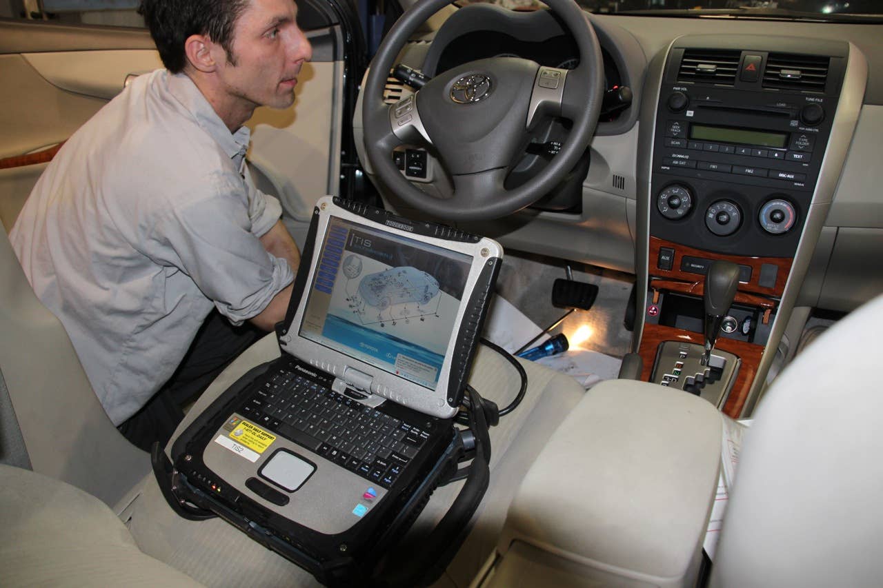 Kropp re-installs the accelerator pedal and connects the diagnostic computer.